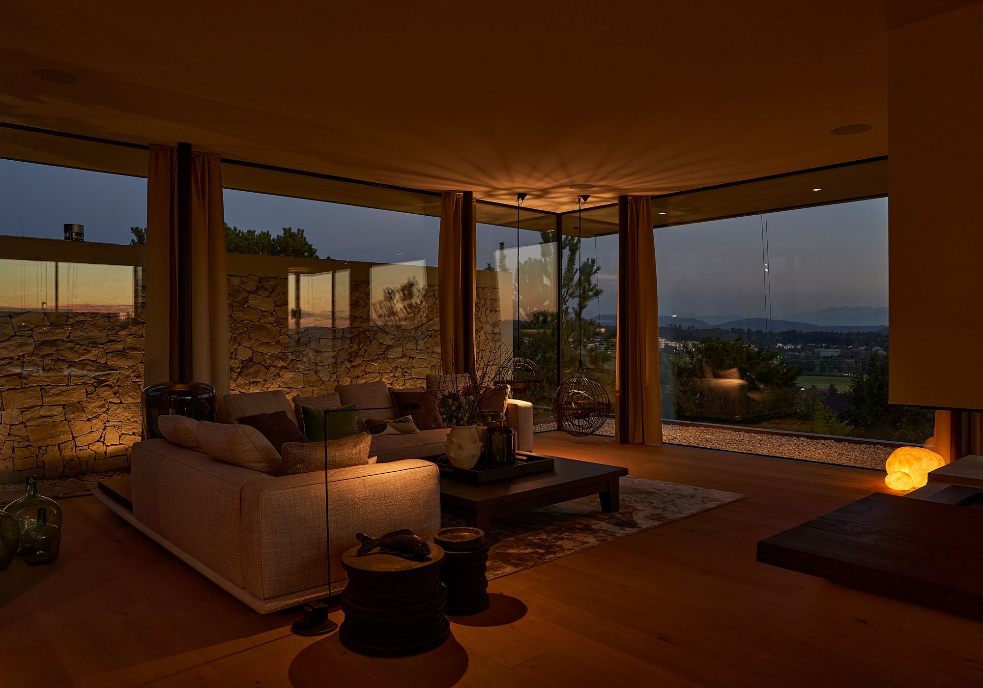 Living room with natural stone wall and panoramic windows – Single-family house in Uitikon