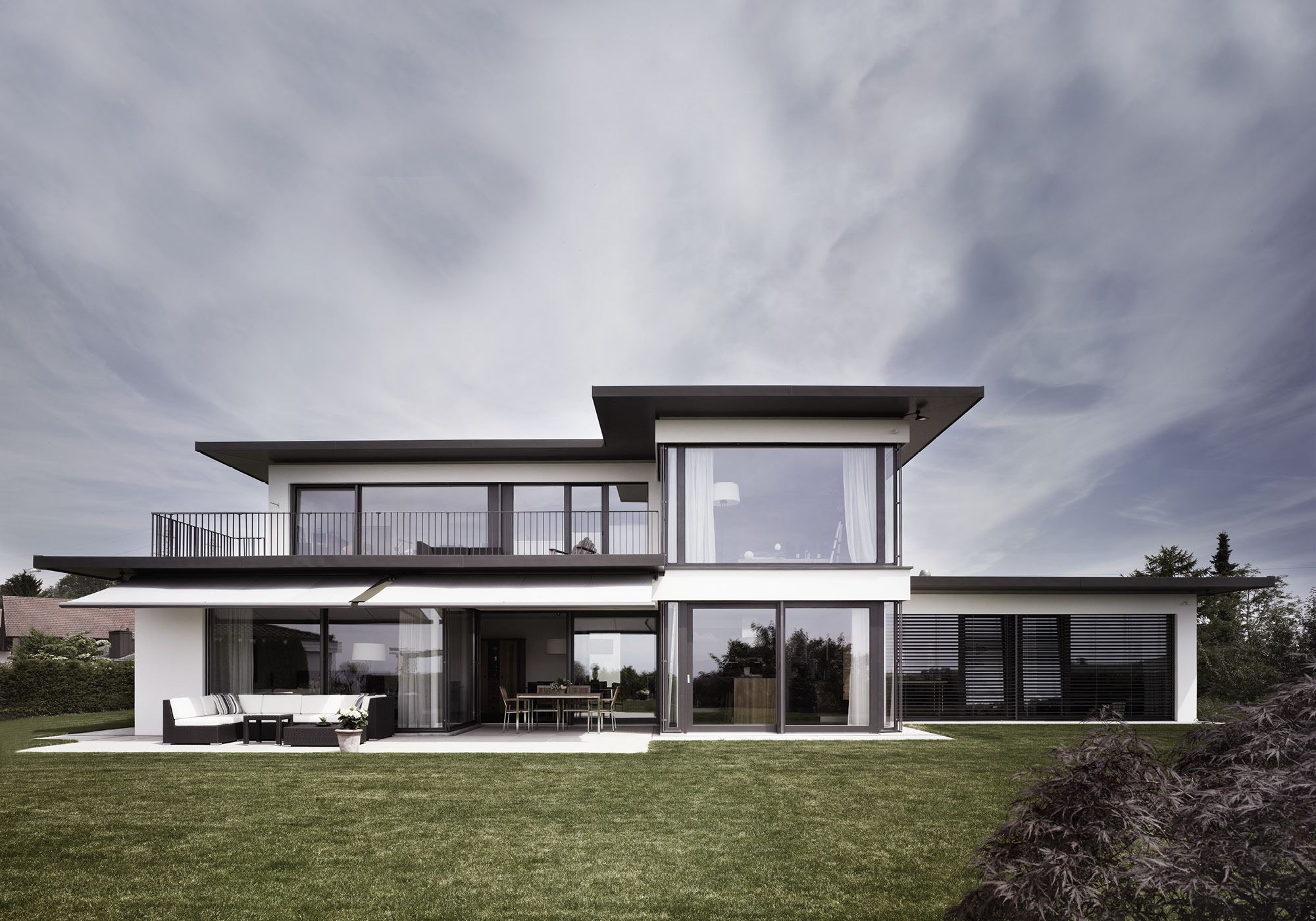 White house with low hipped roofs above the lawn – Single-family house in Russikon