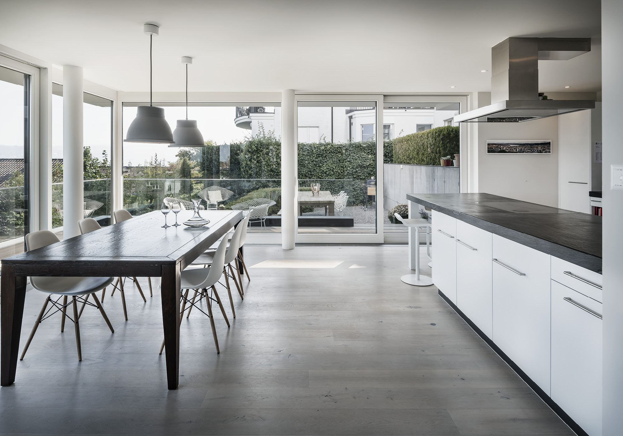 Kitchen with white fronts and dining table by the terrace – Interiors and landscape, Kilchberg