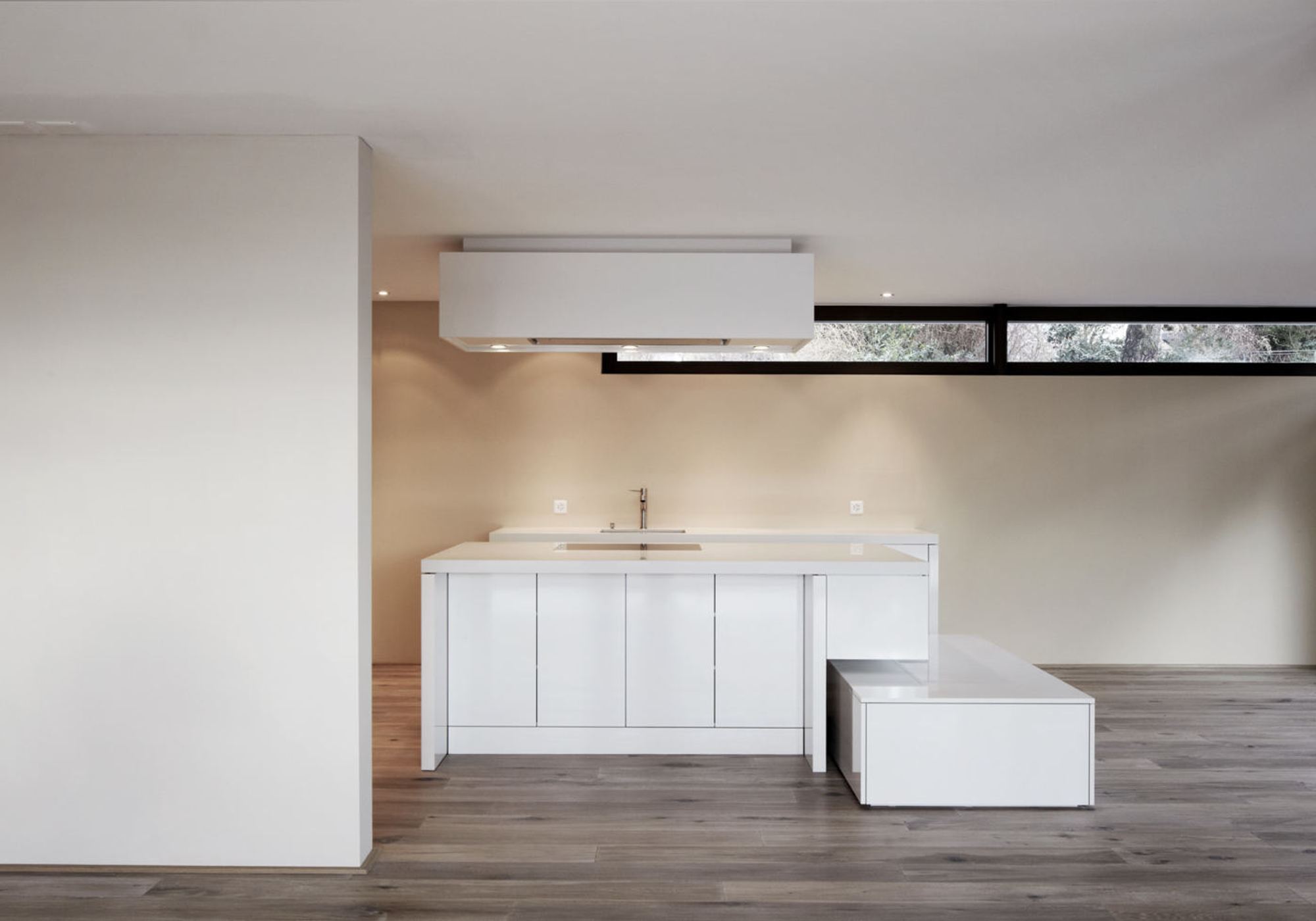 White kitchen island with extractor hood and ribbon window – Apartment building in Uitikon