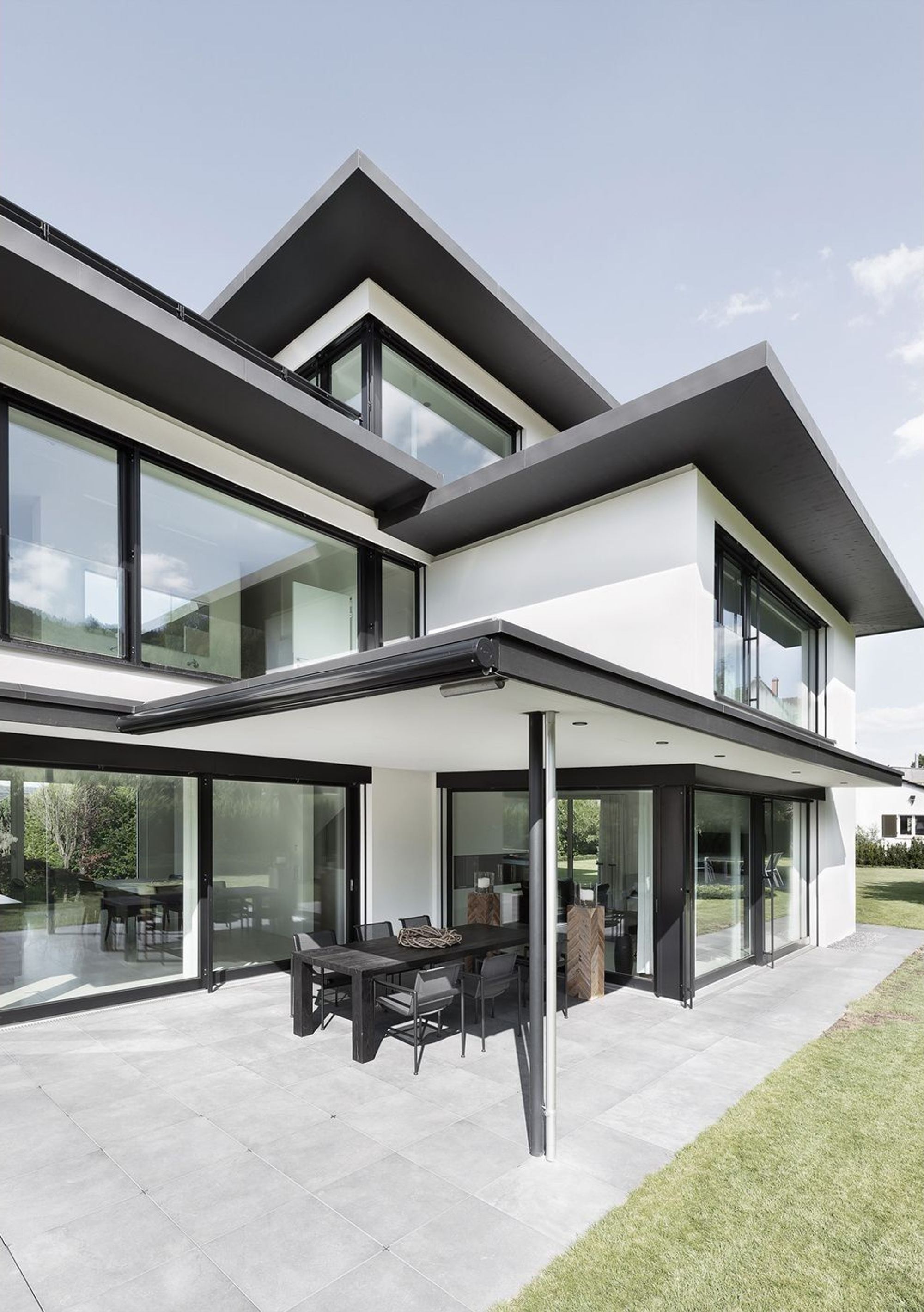 Covered seating area below wide overhanging roofs – Single-family house in Zürich