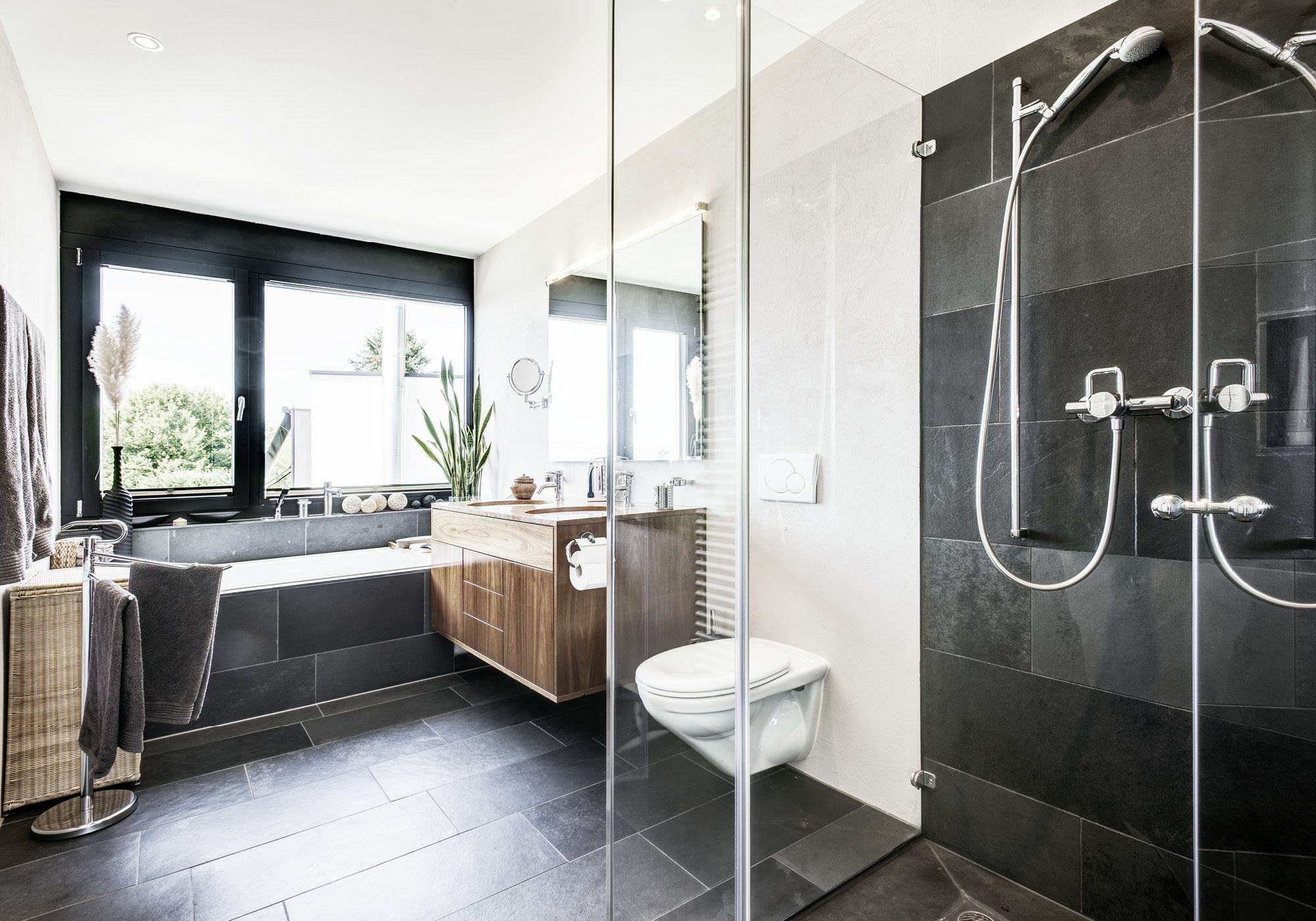Bathroom with glass shower and dark tiles – Single-family house in Uitikon
