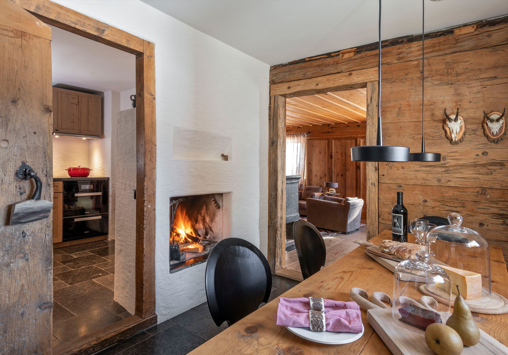 Dining area with timber table and open fireplace – Historic conversion in Fidaz