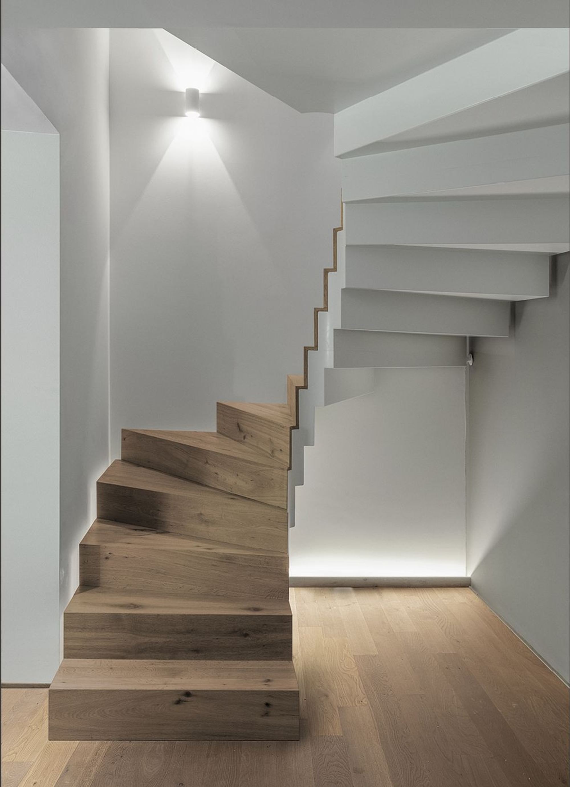Winding timber staircase with wall light – Interiors and landscape, Stallikon