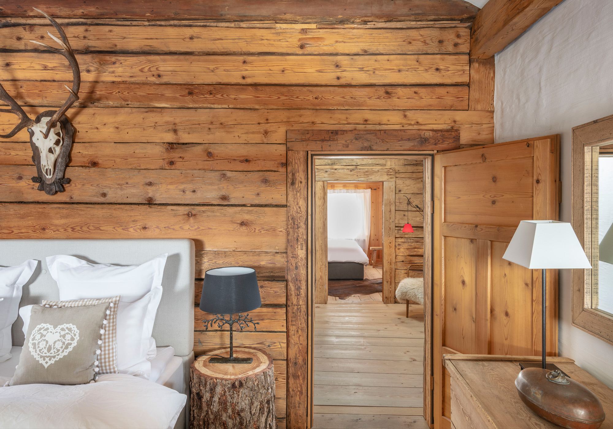 Bedroom with reclaimed timber wall and antlers – Historic conversion in Fidaz