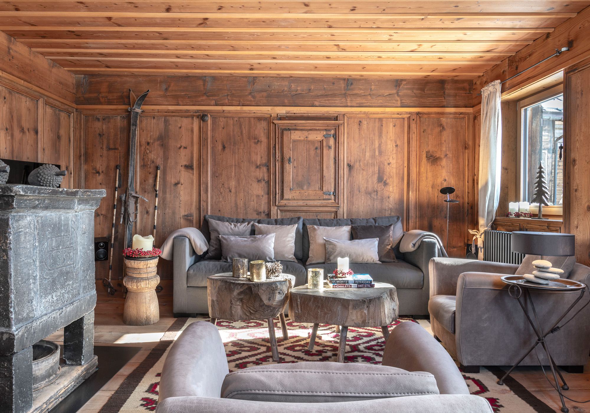 Living room with sofa, timber ceiling and stone stove – Historic conversion in Fidaz