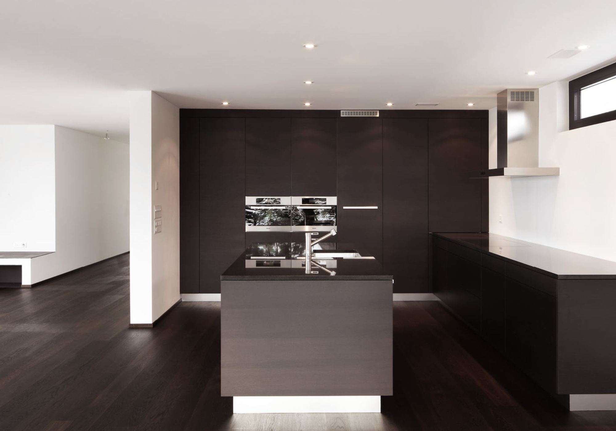 Kitchen with dark fronts and island – Apartment building in Uitikon