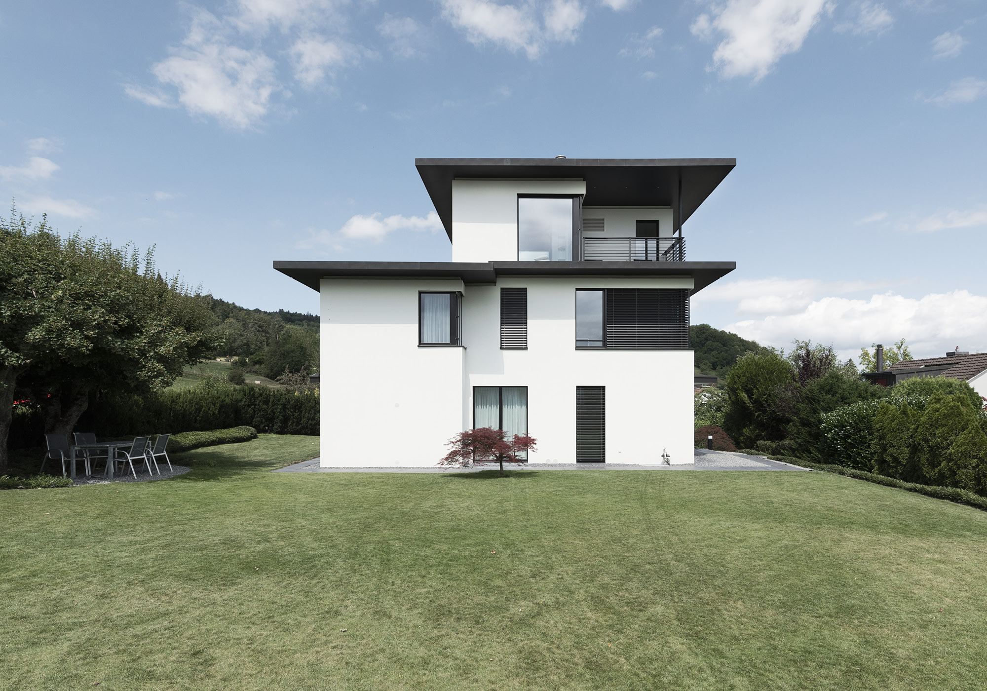 White house with cantilevered roofs above the lawn – Single-family house in Zürich