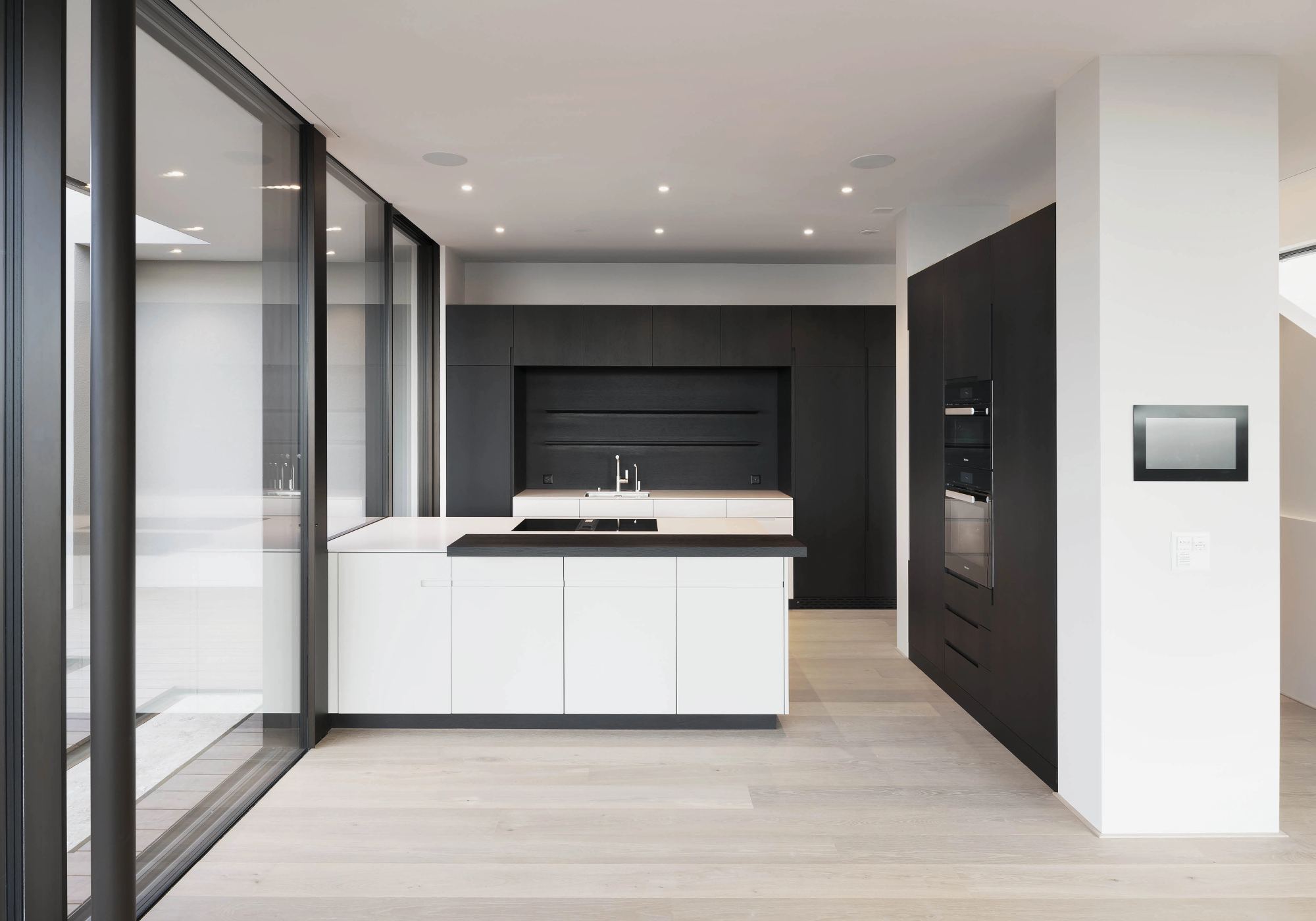 Kitchen with white island and dark back wall – Single-family house in Uitikon