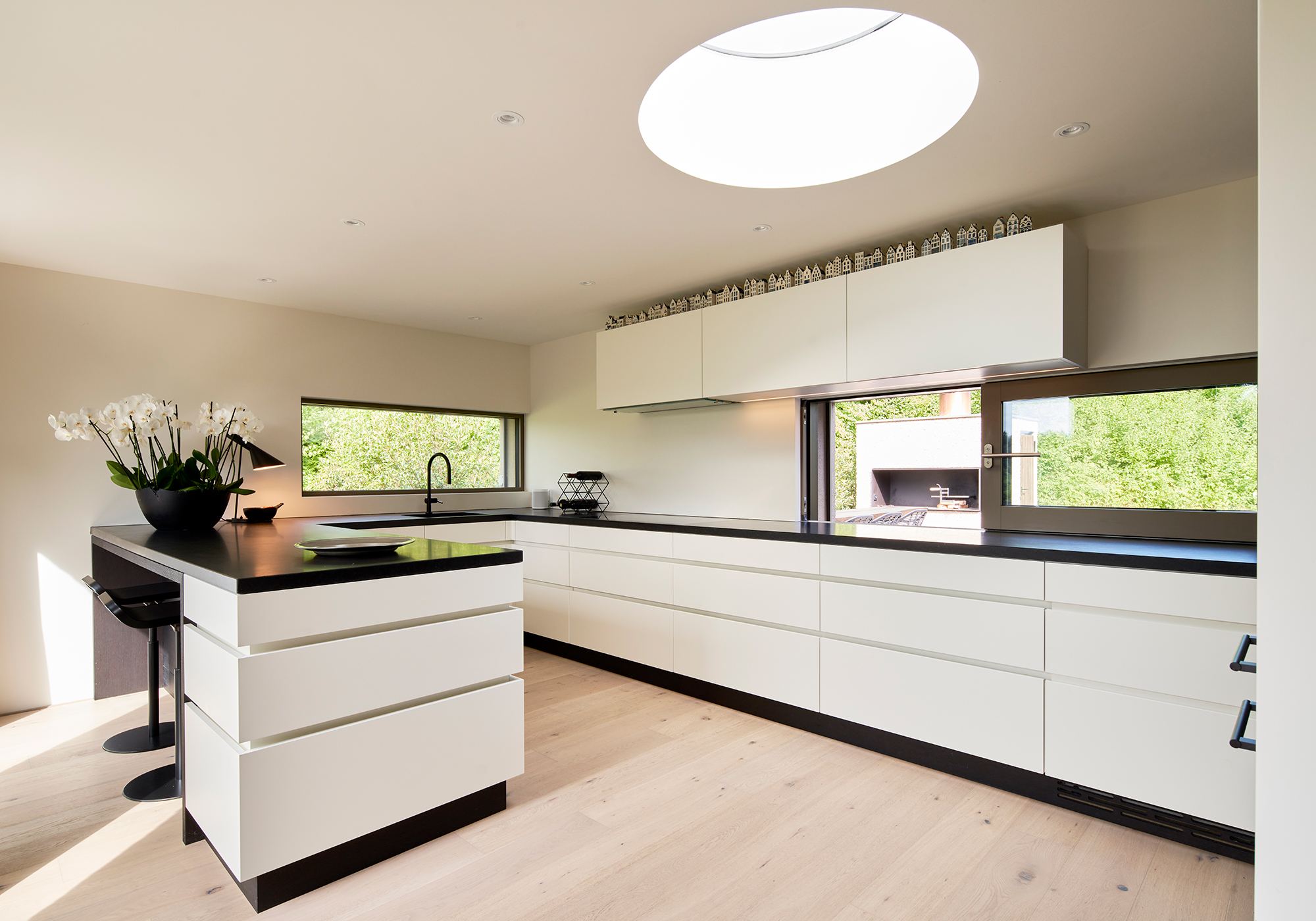 Kitchen with white fronts and circular skylight – Interiors and landscape, Wettswil