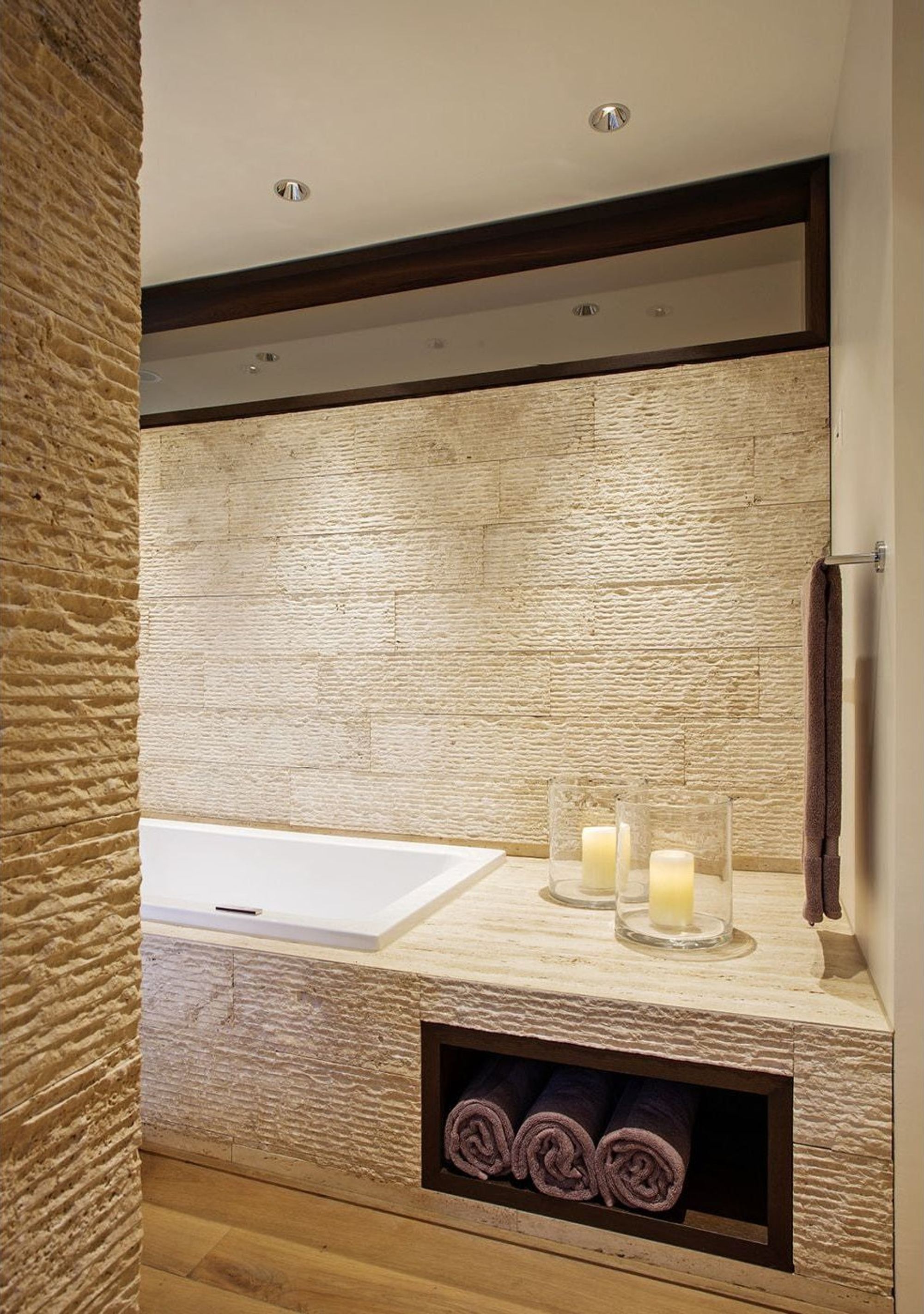 Bathtub with natural stone wall and candles – Apartment building in Uitikon