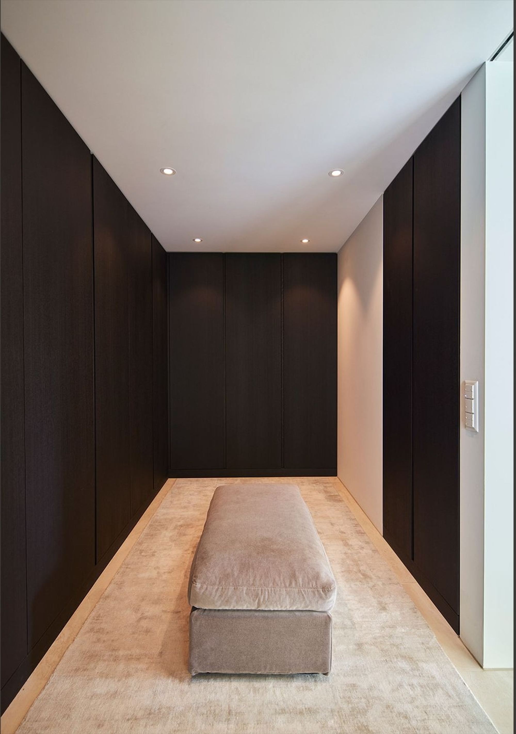 Dressing room with dark wardrobes and upholstered bench – Interiors and landscape, Wettswil