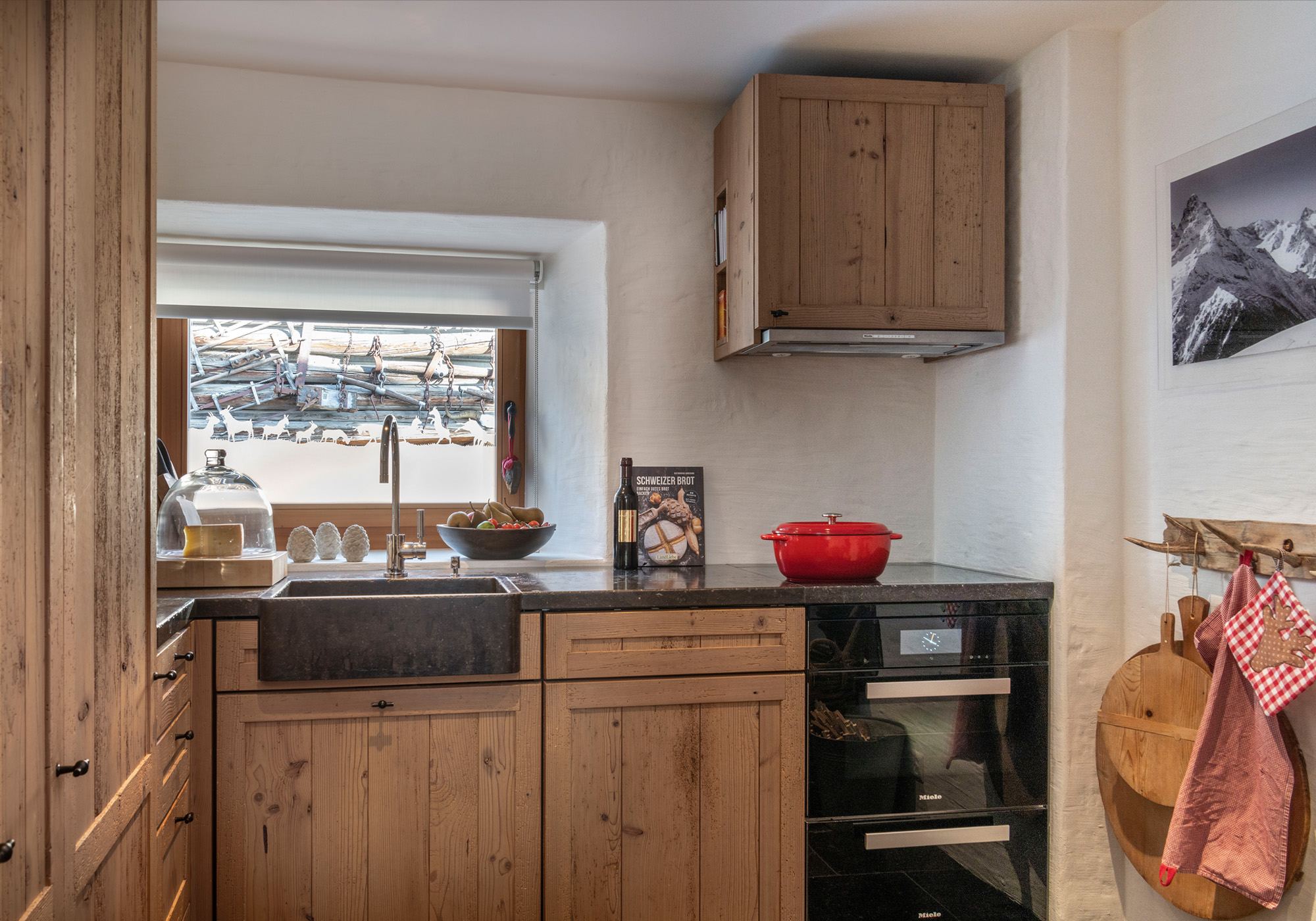 Kitchen with timber fronts and mountain view – Historic conversion in Fidaz