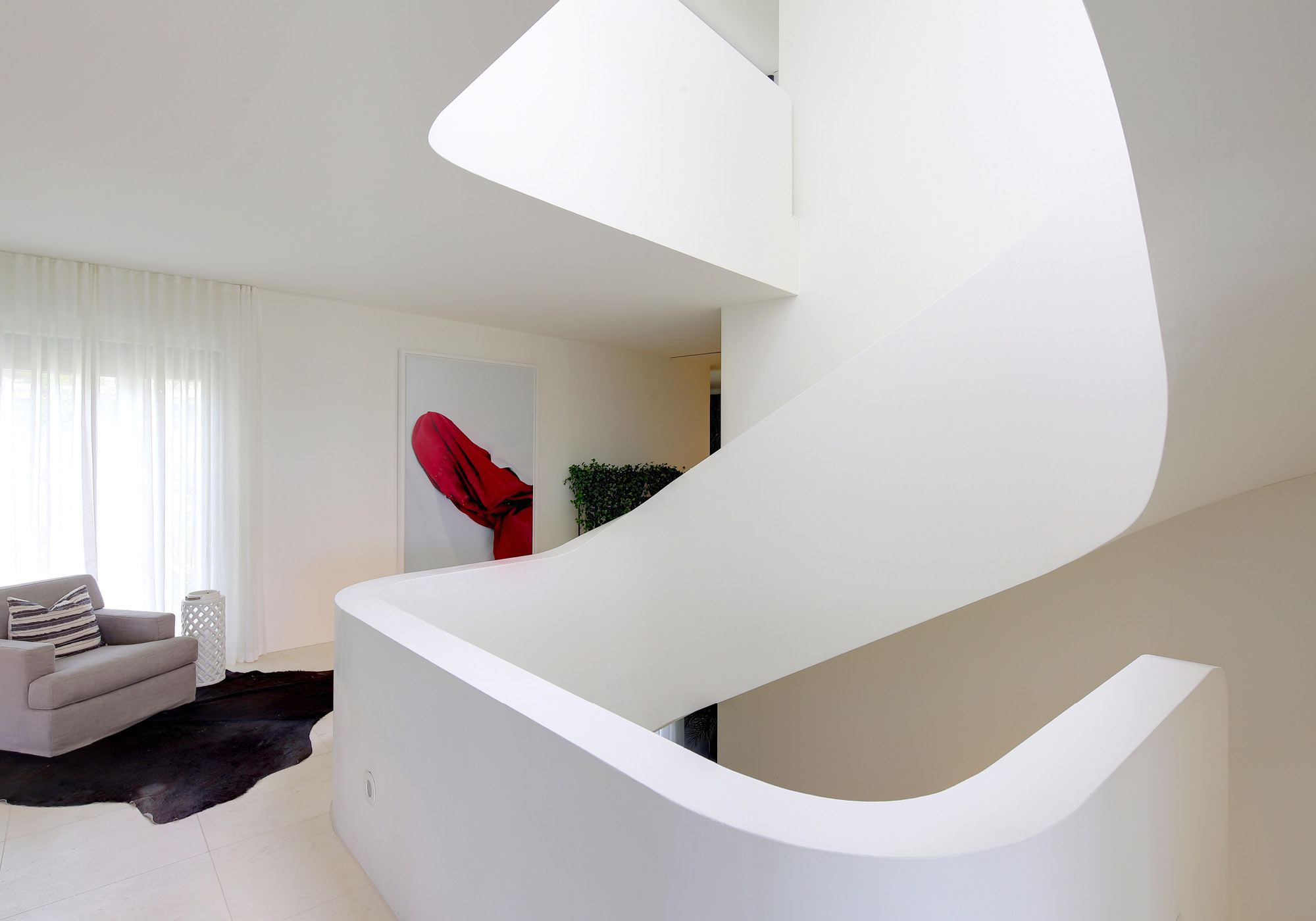 Sweeping white staircase with armchair – Single-family house in Meilen