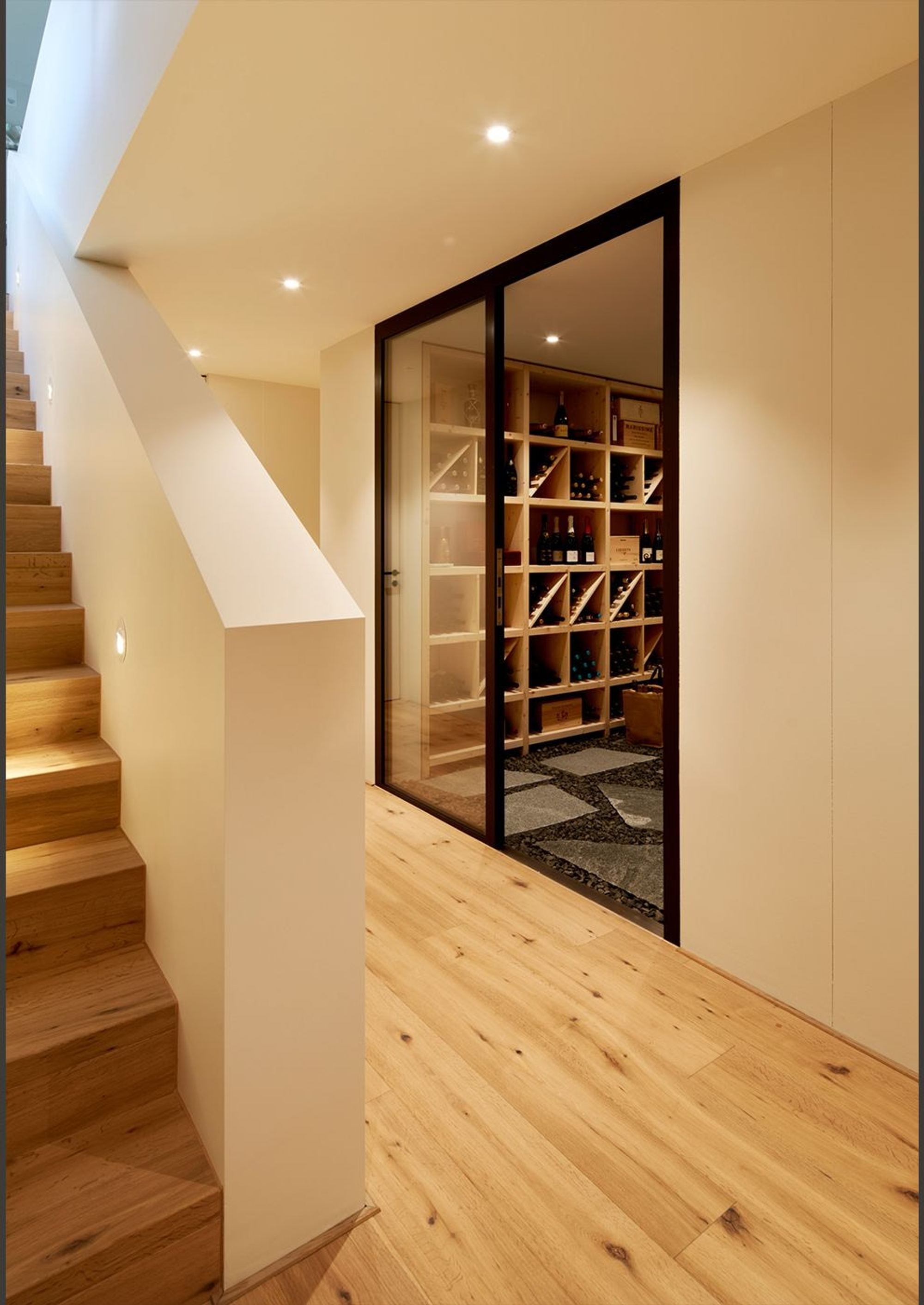 Staircase with view into the glazed wine store – Single-family house in Herrliberg