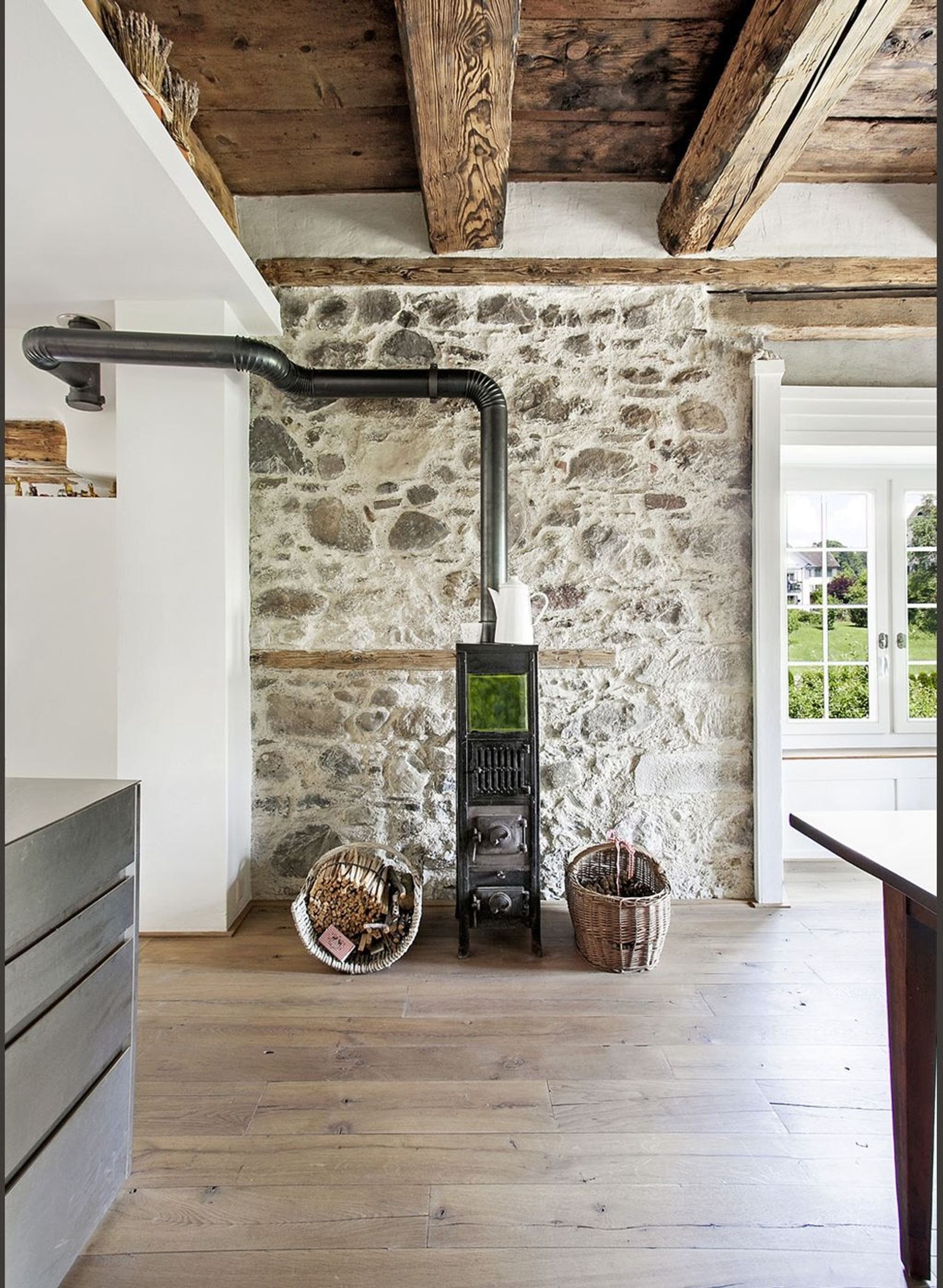 Wood stove in front of an old rubble stone wall – Historic conversion in Uerikon