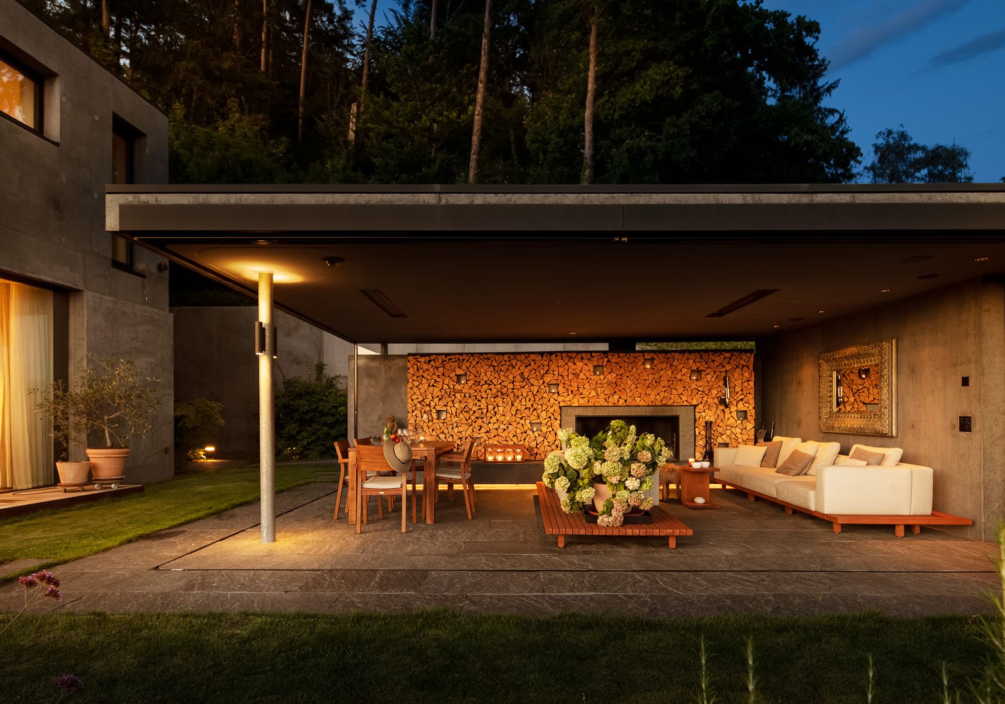 Covered outdoor room with fireplace and lounge in the evening – Single-family house in Uitikon