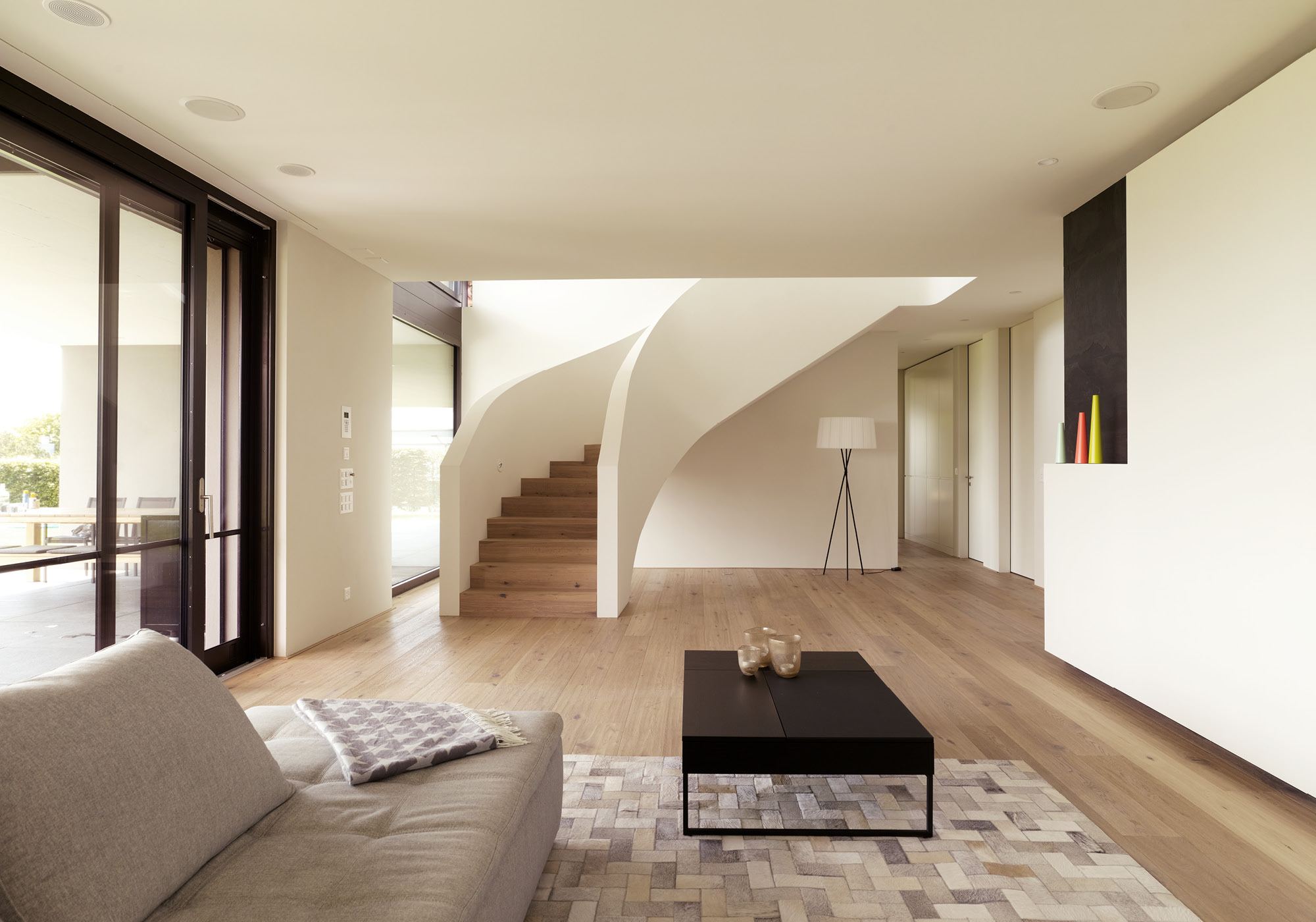Living room with sofa and curved staircase – Single-family house in Oberwil-Lieli