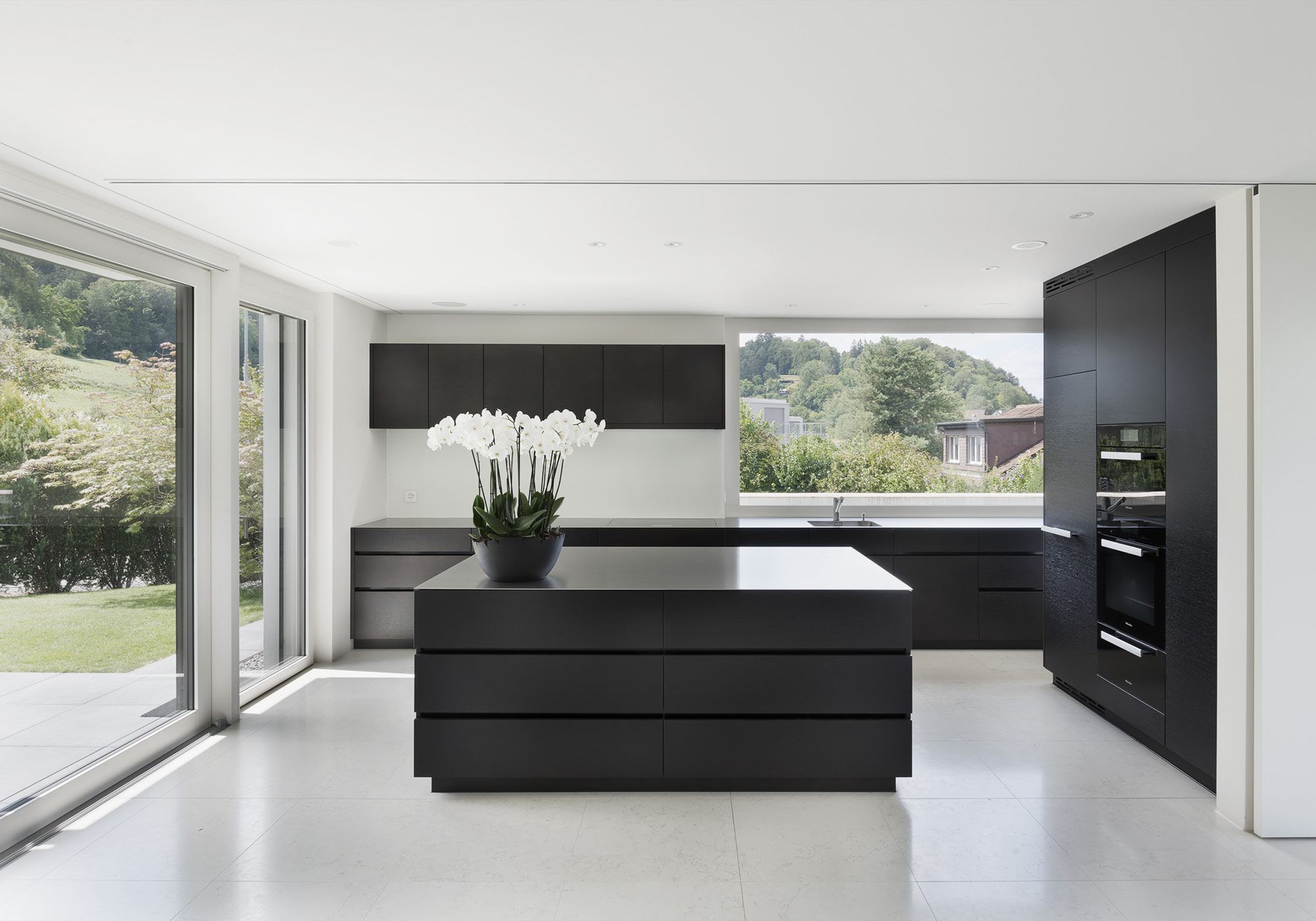 Kitchen with black island and garden view – Single-family house in Zürich