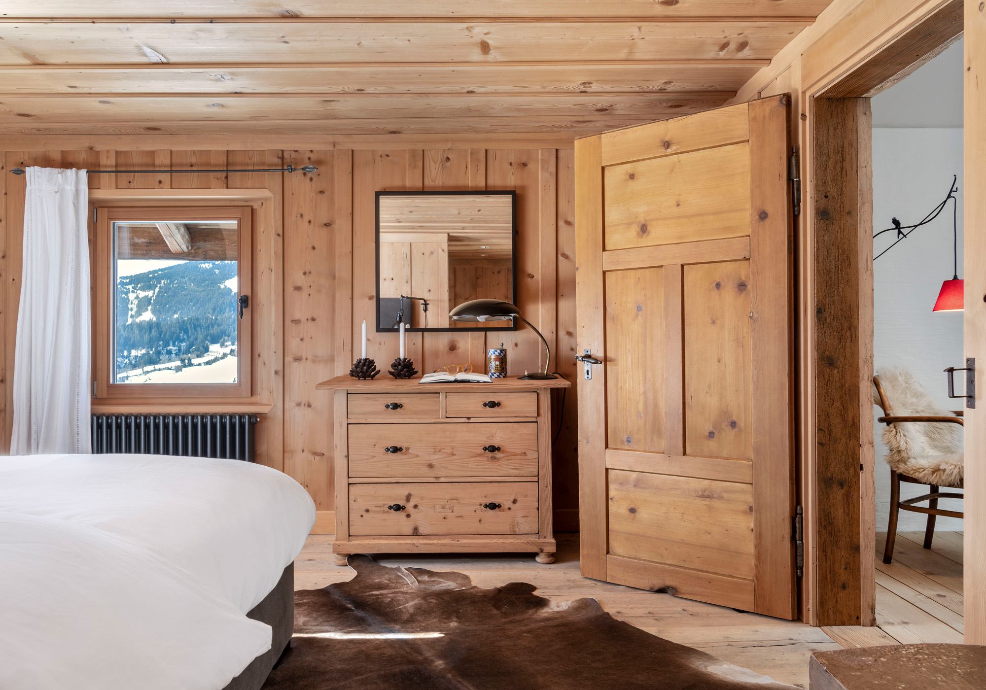 Bedroom with timber chest of drawers and valley window – Historic conversion in Fidaz