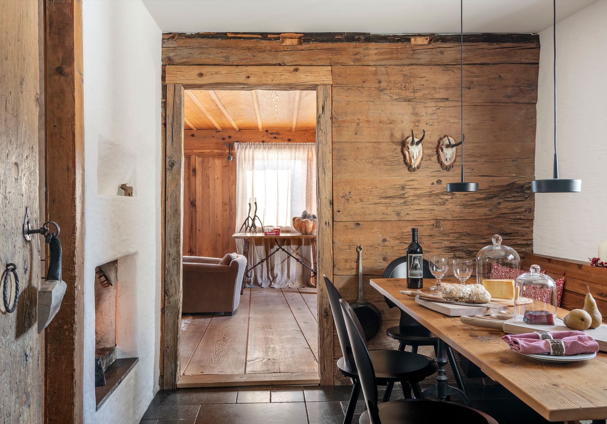 Long dining table with view into the parlour – Historic conversion in Fidaz