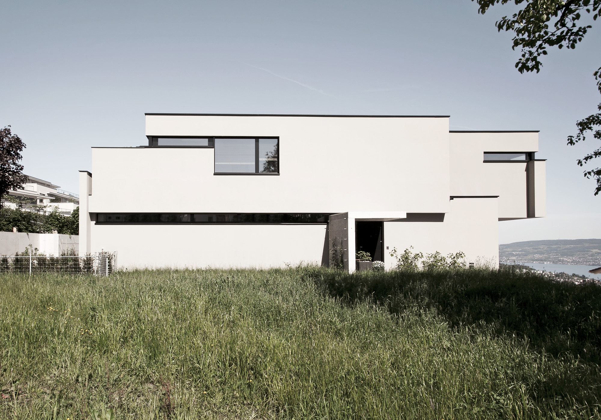 White cube behind tall grass – Single-family house in Schindellegi