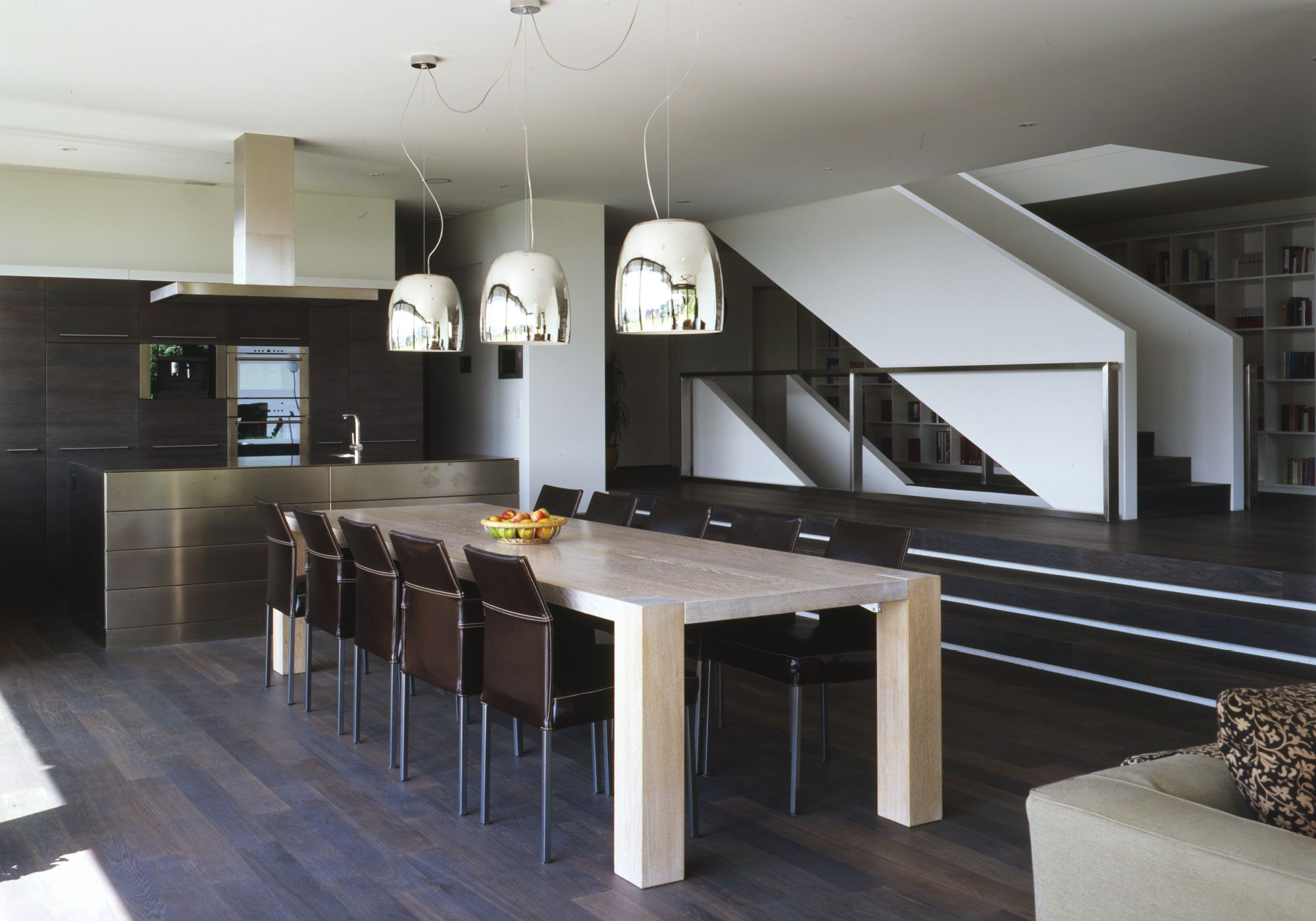 Long dining table beneath chrome pendant lights – Single-family house in Bonstetten