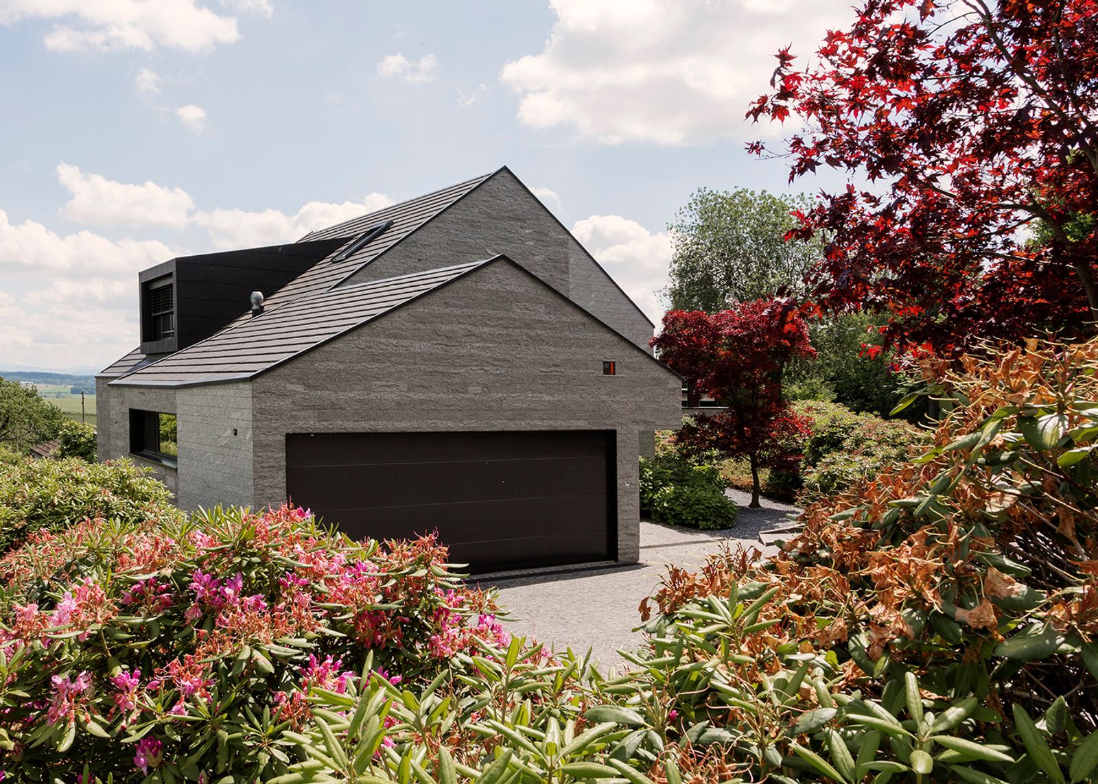 Garage with gabled roof behind flowering shrubs