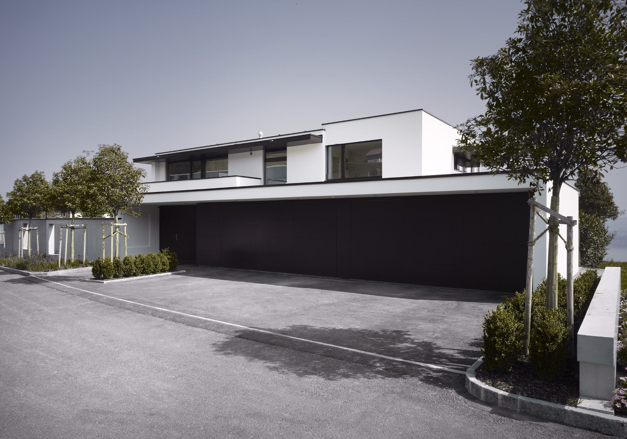 Garage with dark door and forecourt – Single-family house in Schindellegi