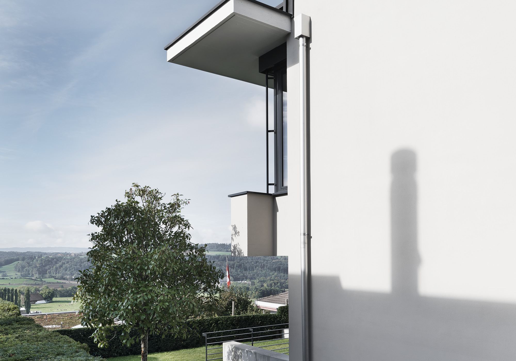 White wall with cast shadow and view into the valley – Single-family house in Uitikon