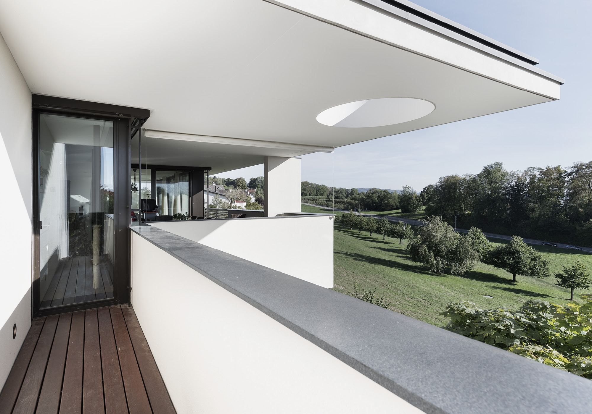 Balcony with timber floor and circular roof light – Single-family house in Uitikon