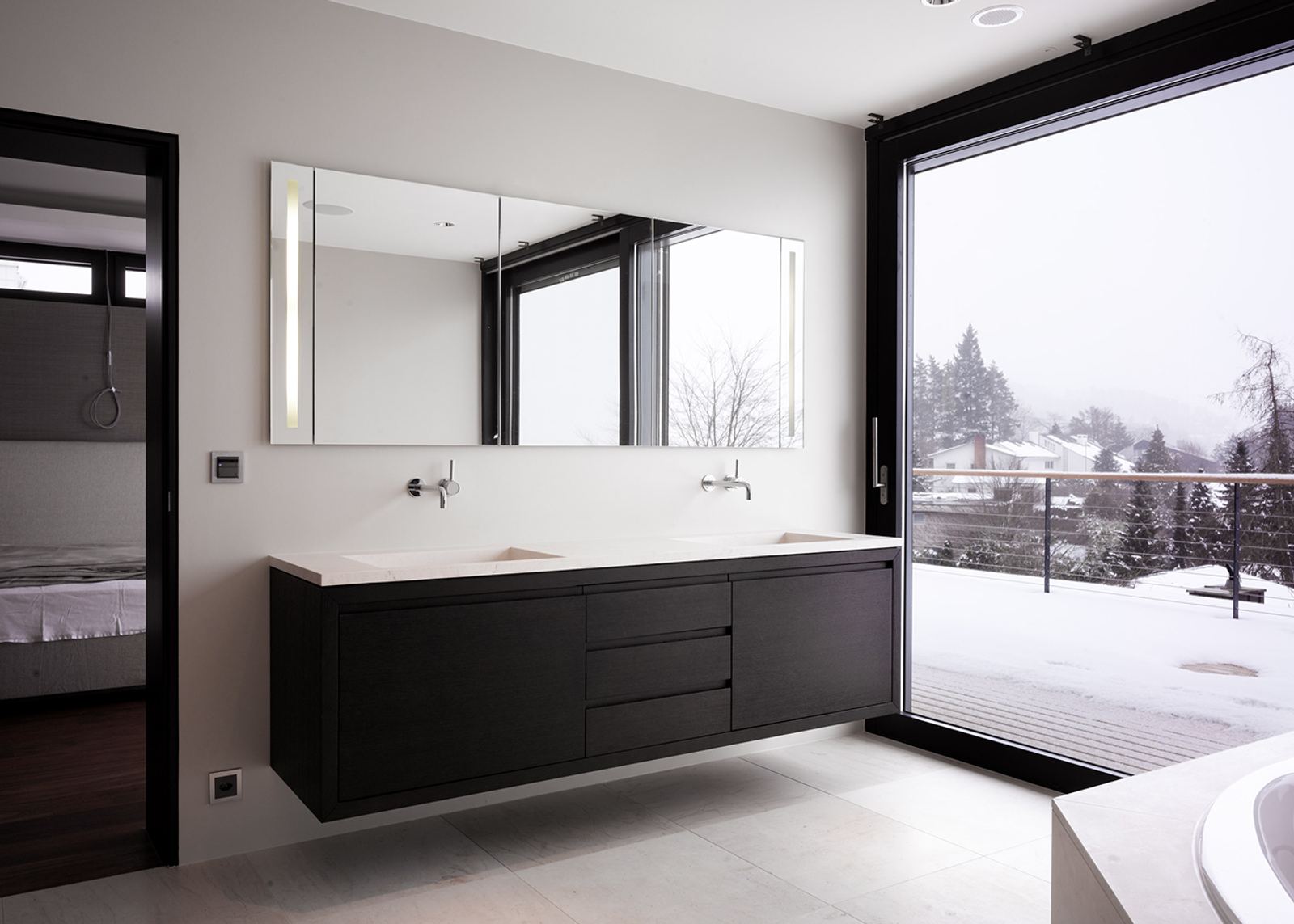 Dark vanity with a snowy view outside