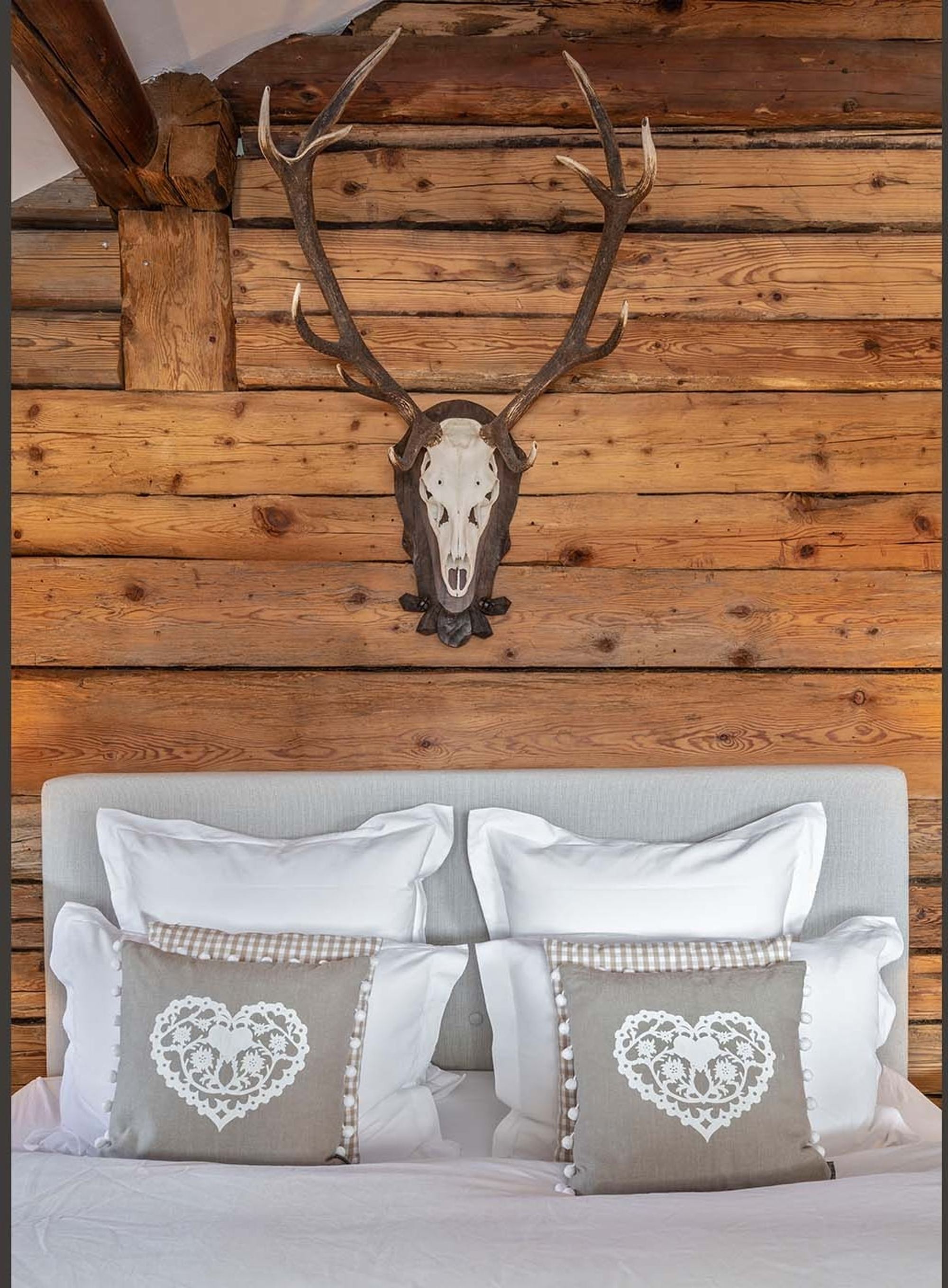 Bedhead with heart cushions below the antlers – Historic conversion in Fidaz