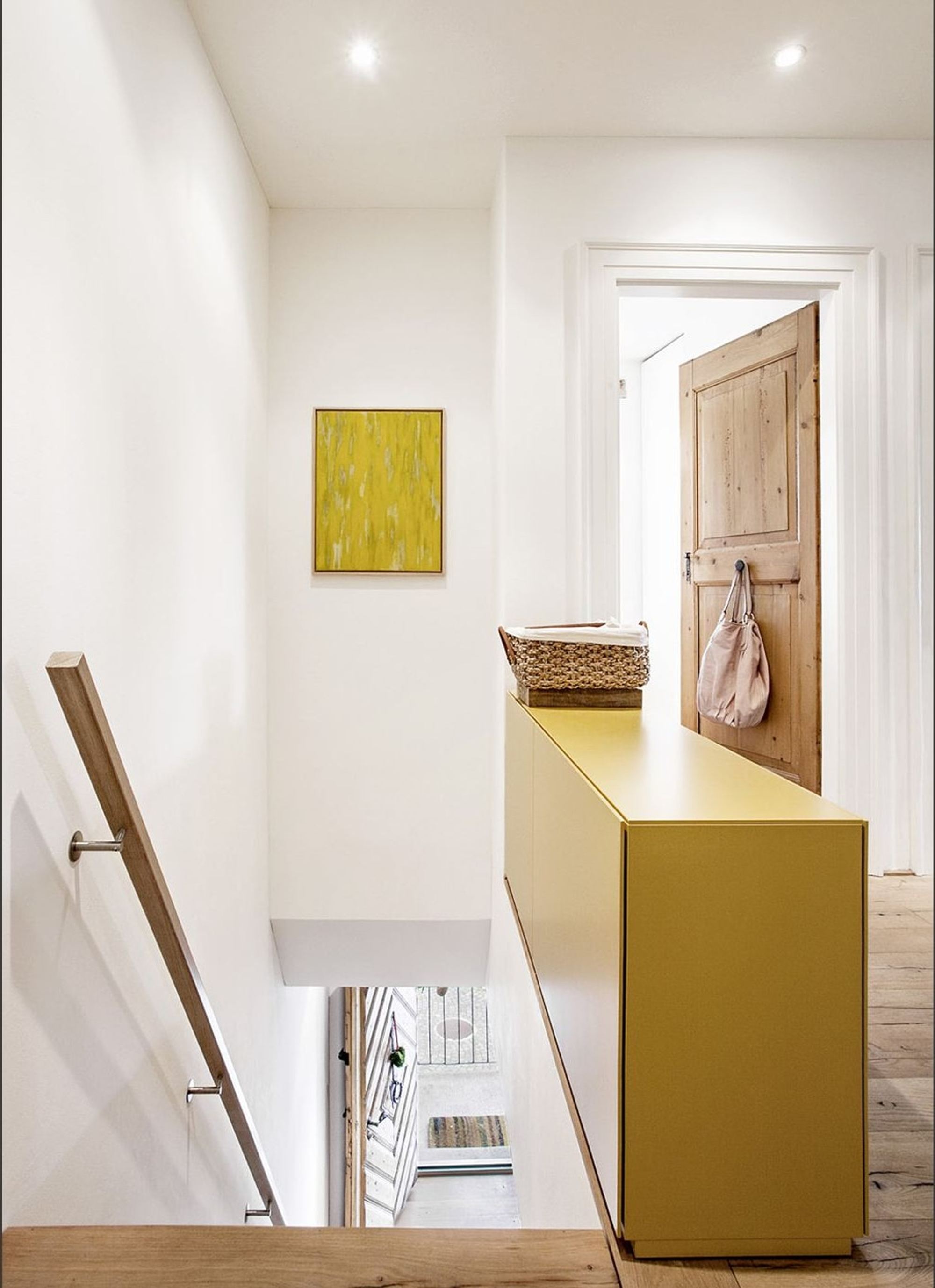 Stair landing with yellow sideboard and timber door – Historic conversion in Uerikon