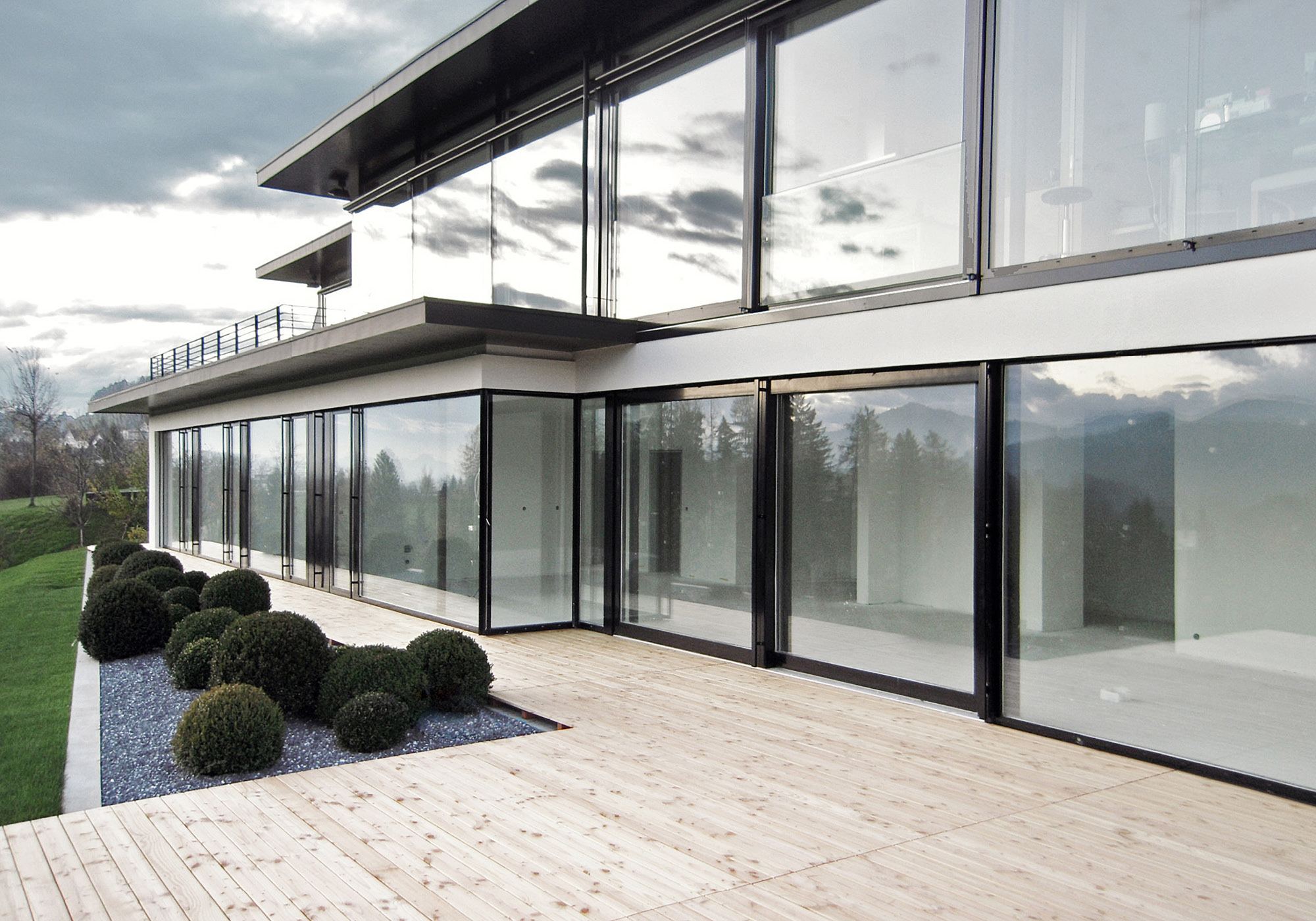 Glazed facade with timber terrace and box balls – Single-family house in Teufen