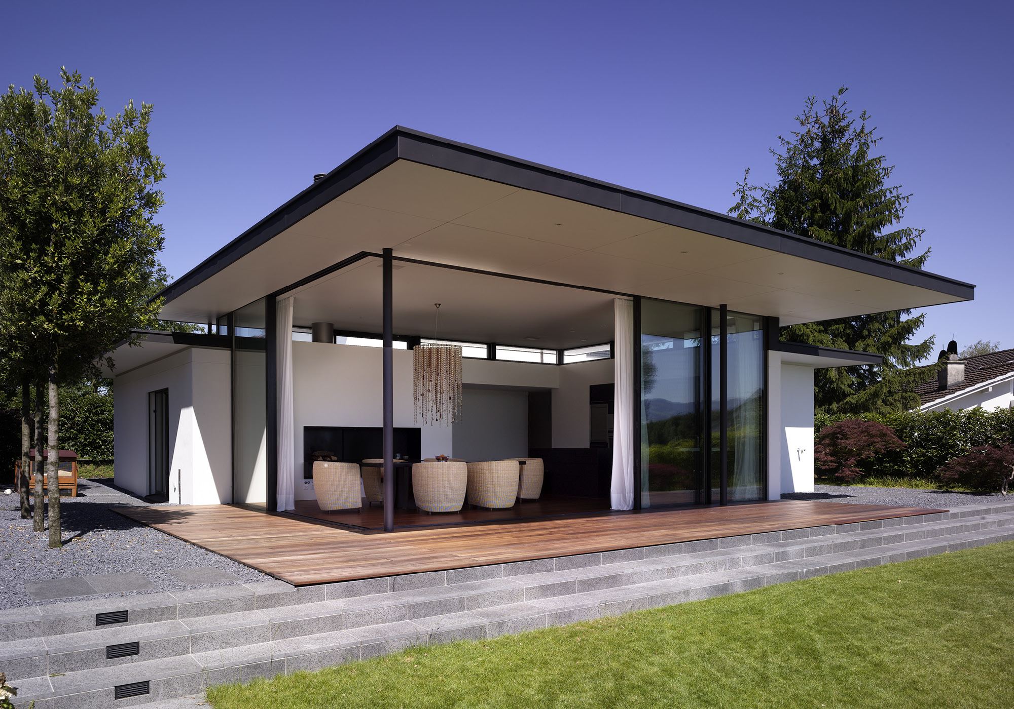 Glass front with timber deck at dusk – Single-family house in Lachen
