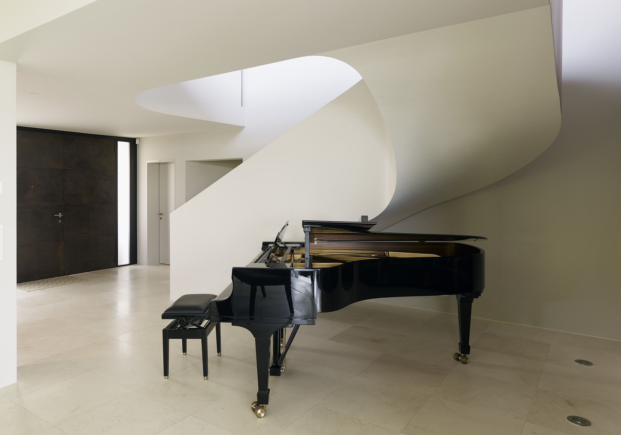 Grand piano in front of the sweeping white staircase – Single-family house in Uitikon