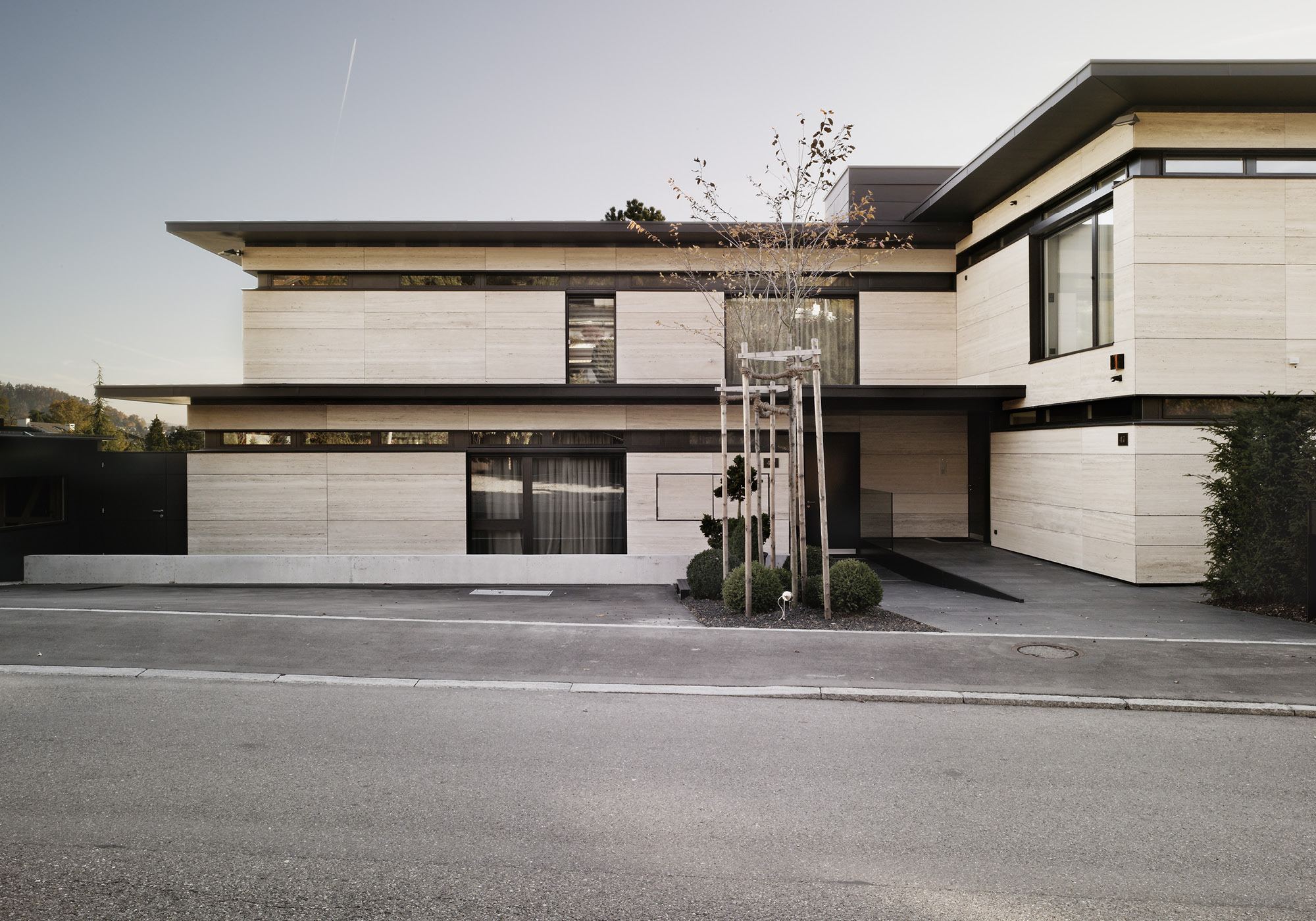 Street facade with light natural stone and canopies – Single-family house in Uitikon