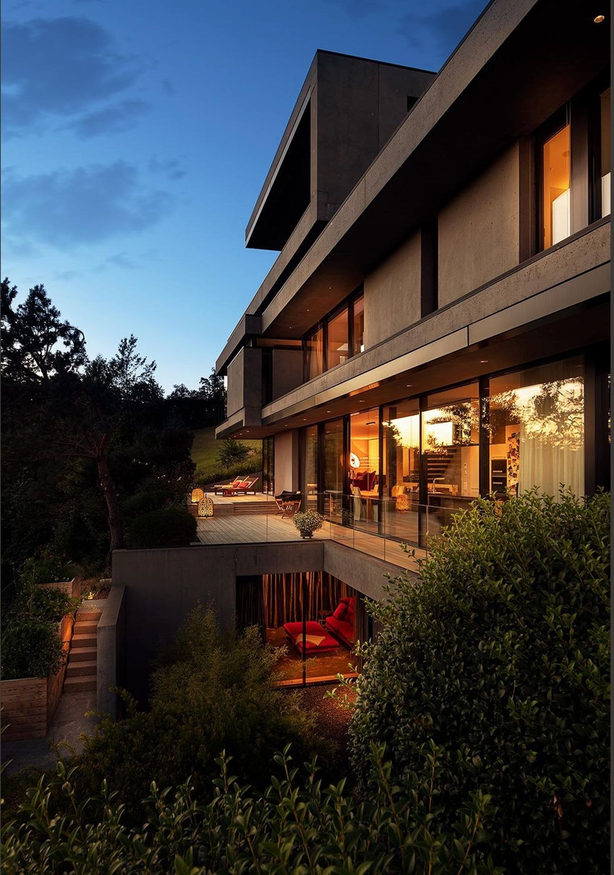 Stepped facade with balconies at dusk – Single-family house in Uitikon