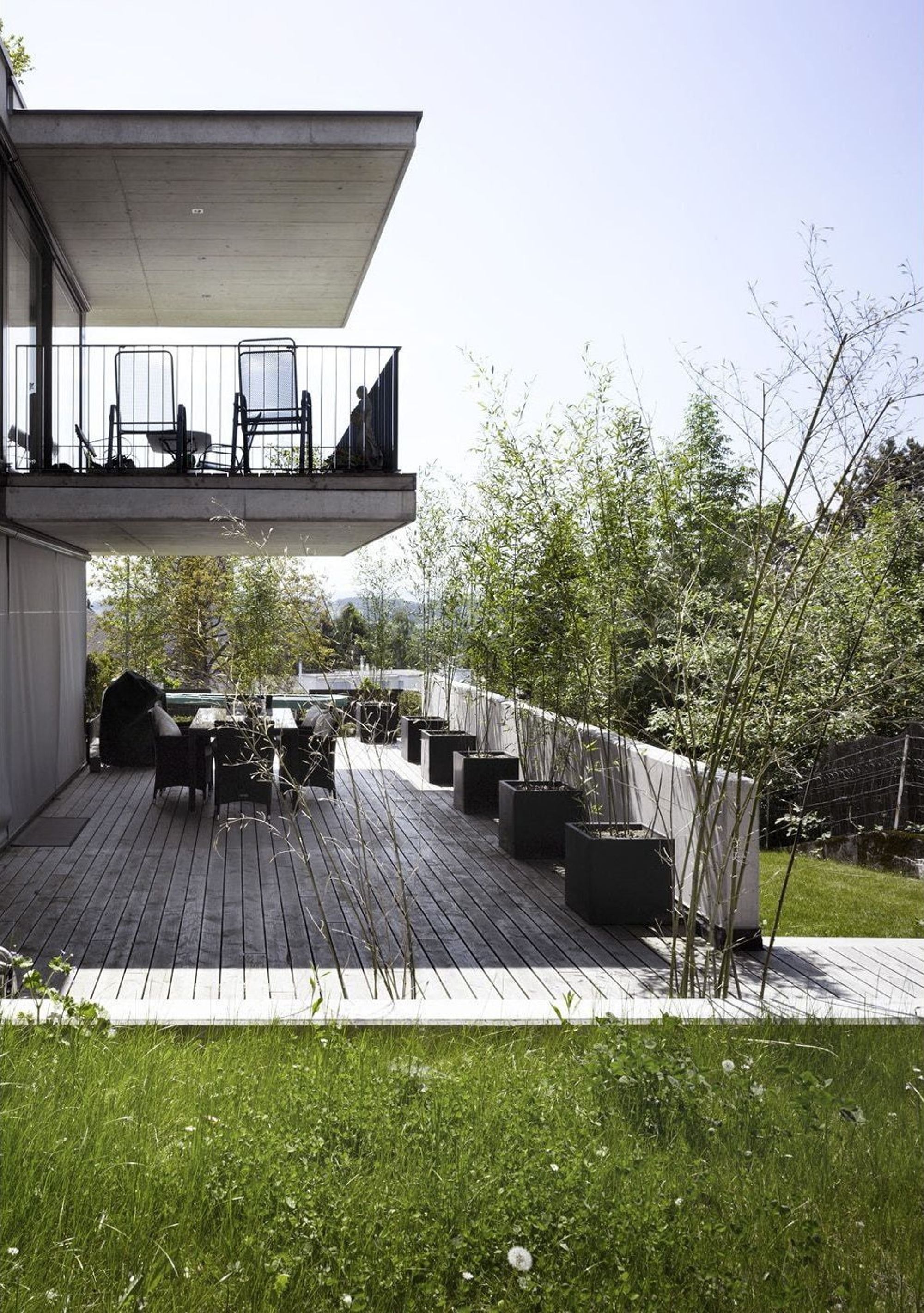 Timber terrace with table below the balcony – Apartment building in Uitikon