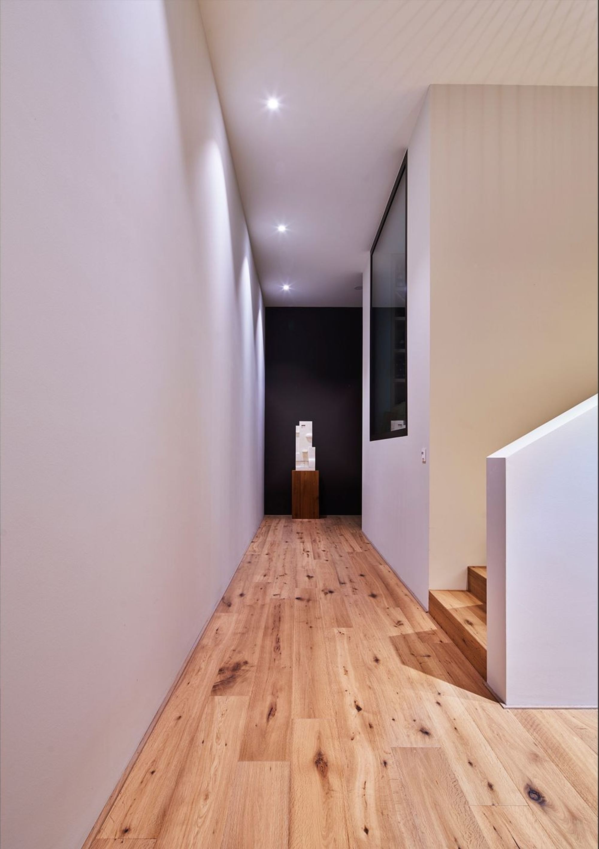Narrow hallway with timber floor and sculpture – Single-family house in Herrliberg