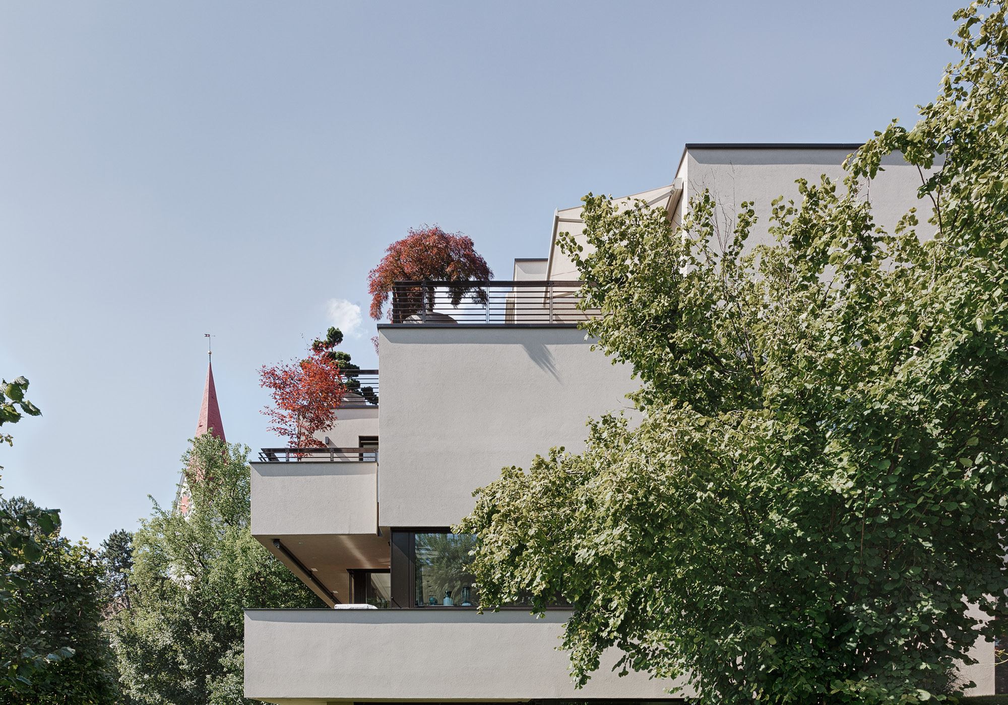 House corner with roof garden and church tower behind – Single-family house in Zürich