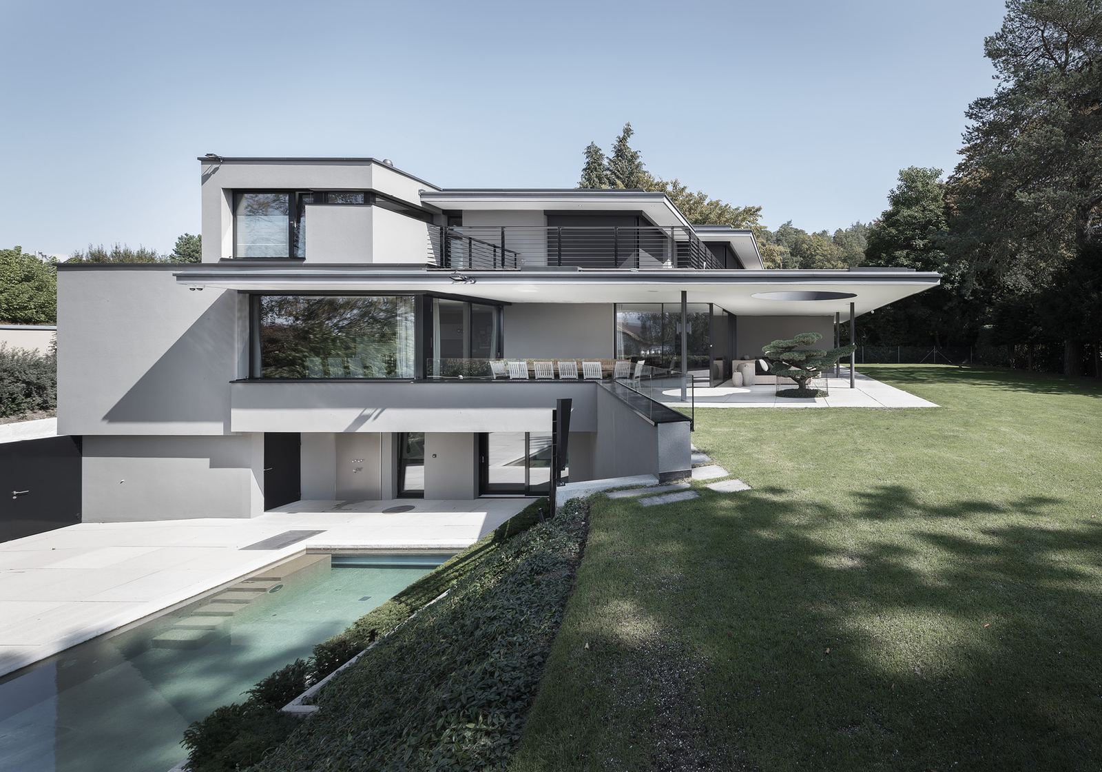 Pool by the lawn in front of the flat-roofed house