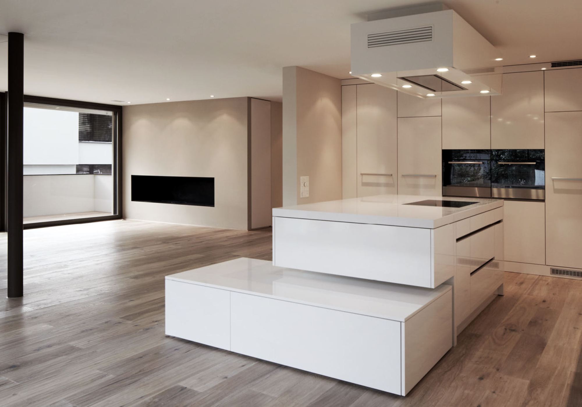 Open kitchen with white island and fireplace – Apartment building in Uitikon