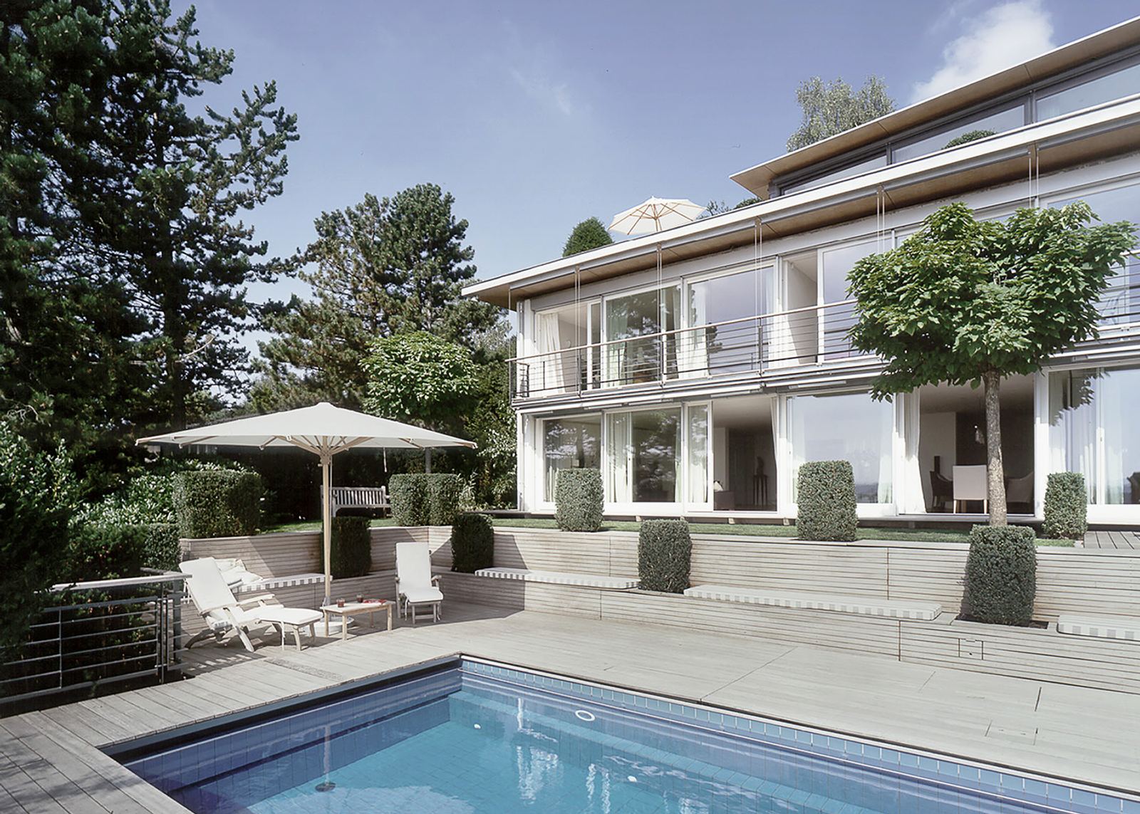Pool with loungers and parasol in front of the house
