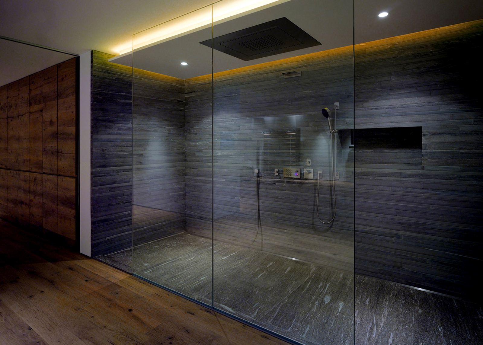 Large shower with glass wall and dark stone