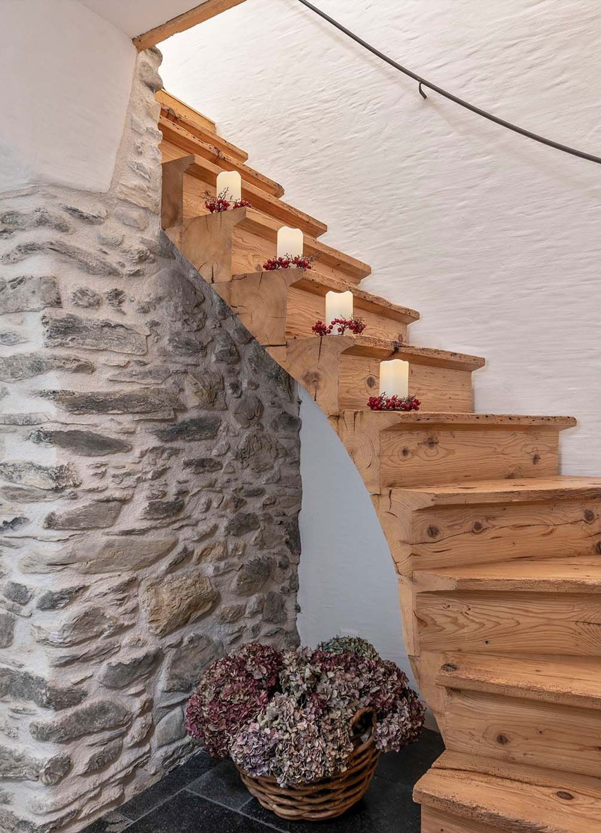 Timber staircase along a natural stone wall – Historic conversion in Fidaz
