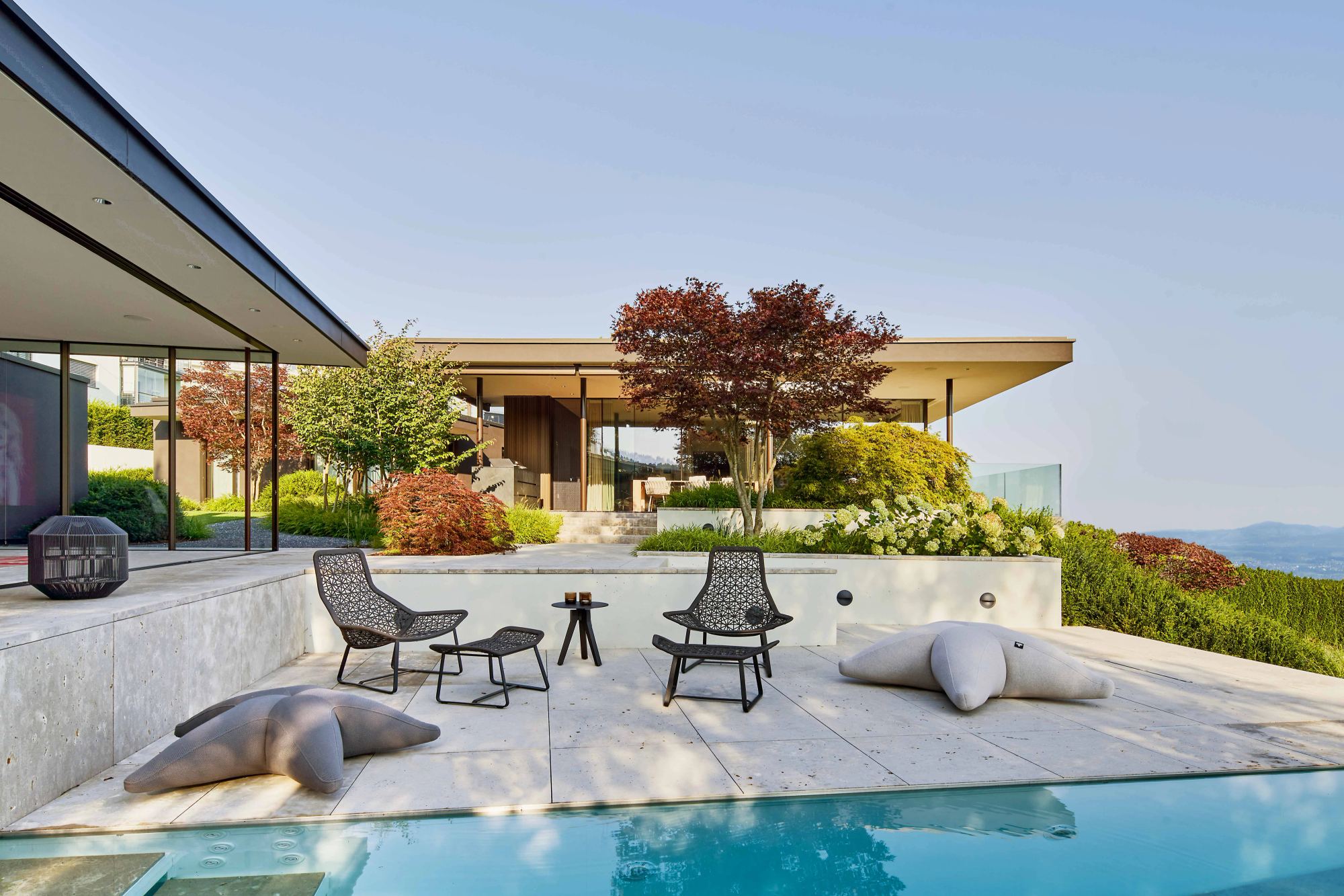 Poolside seating area with lounge furniture and red maple – Single-family house in Schindellegi