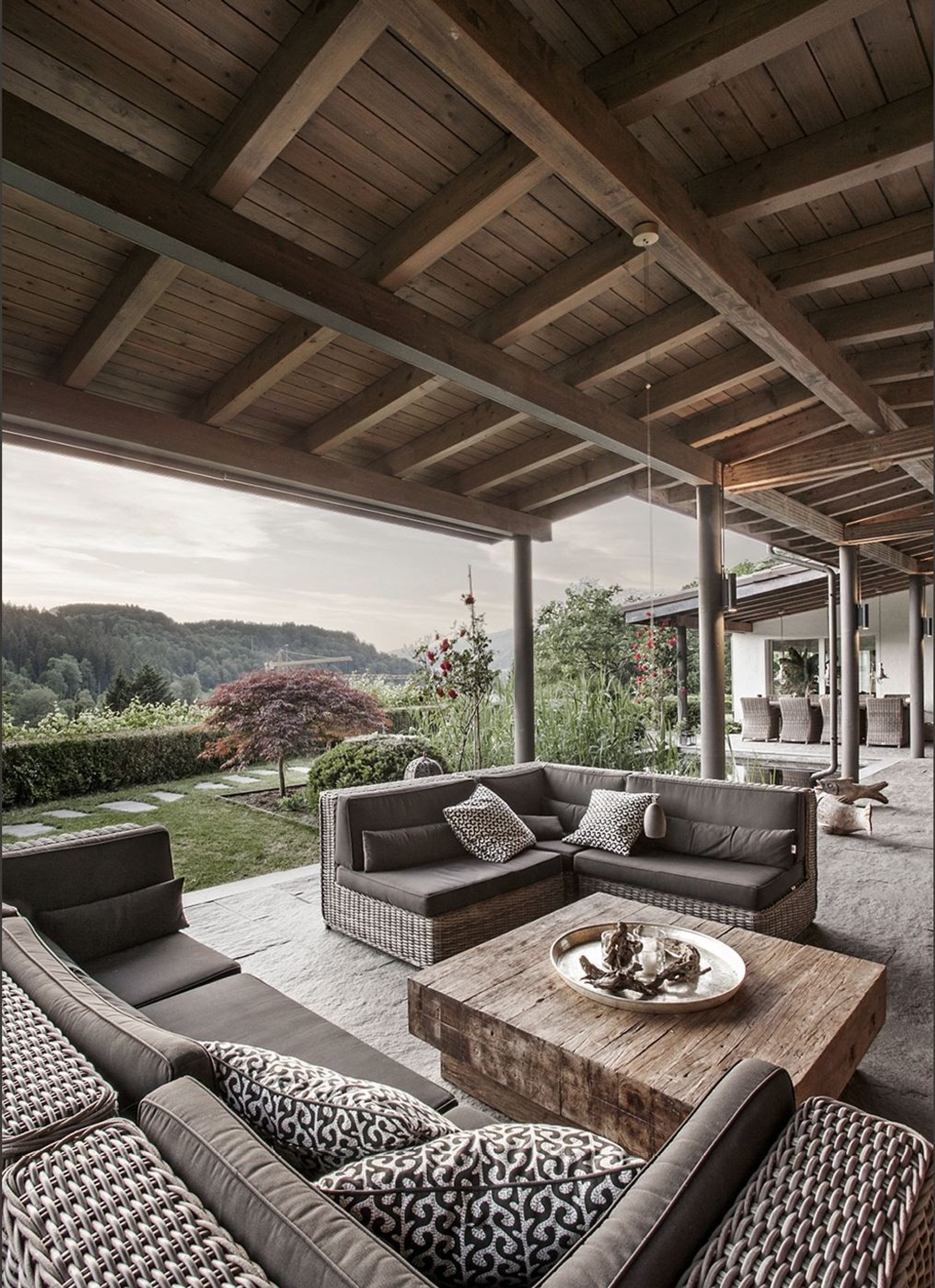 Lounge furniture under the timber roof with view into the valley – Interiors and landscape, Stallikon