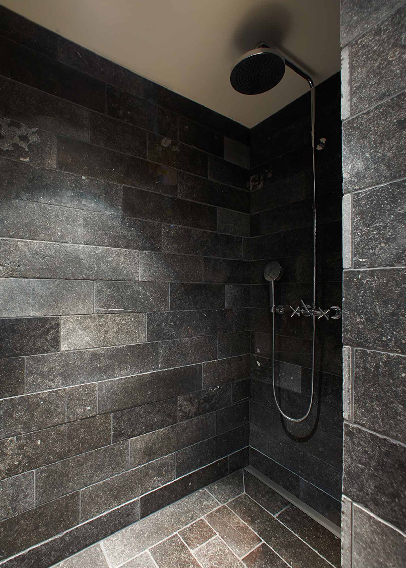 Shower with dark natural stone wall